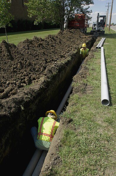 MINOT AIR FORCE BASE, N.D. — Construction workers Jeremy Bickel and Jared Portra replace the piping along Bomber Boulevard here Aug. 19. This overhaul is to replace the deteriorating overhead electrical distribution system, increasing the electrical capacity feed to the new dorms and Missile Wing complex. (U.S. Air Force photo by Airman 1st Class Jesse Lopez)