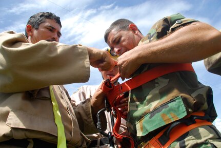 SOTO CANO AIR BASE, Honduras - A Honduran fire fighter from Tegucigalpa helps a Honduran Airman with a rigging harness during a training exercise Aug. 28. The Joint Task Force-Bravo fire department trained with Honduran Air Force and local fire fighters Aug. 25-28 on activities that varied from land navigation to rescue operations. (U.S. Air Force photo by Staff Sgt. Joel Mease)