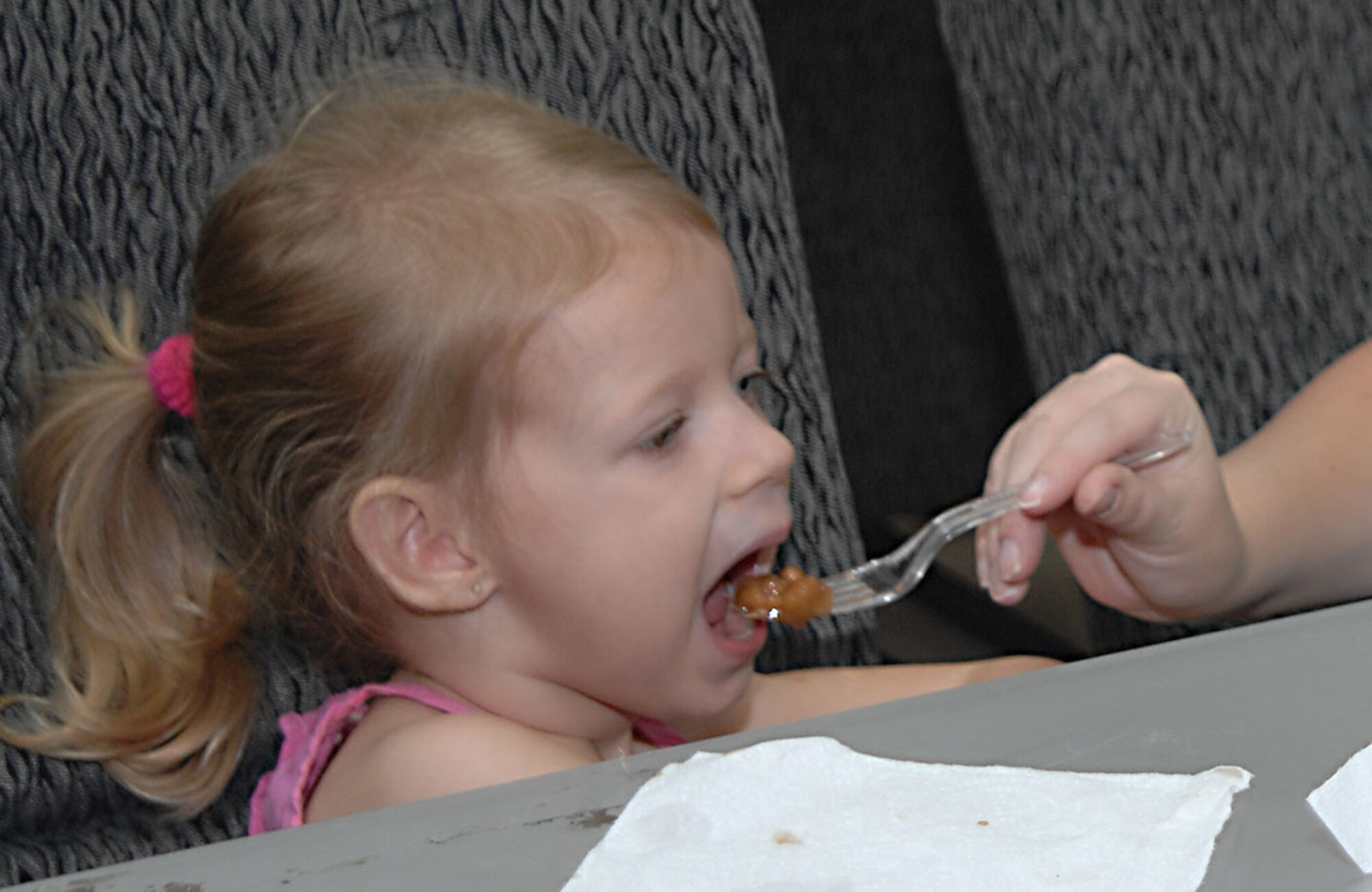CANNON AIR FORCE BASE,N.M.-- Delanie Olin, daughter of Airman 1st Class Lesley Olin, 27th Special Operations Security Forces Squadron, takes a bite of the sweet beans prepared for the First Sergeants' Steak Sale Aug. 22. In addition to the beans, the meal consisted of steak, potatoes, potato bread, and a drink. The annual luncheon was attended by more than 100 people. (U.S. Air Force photo/Airman Maynelinne De La Cruz) 