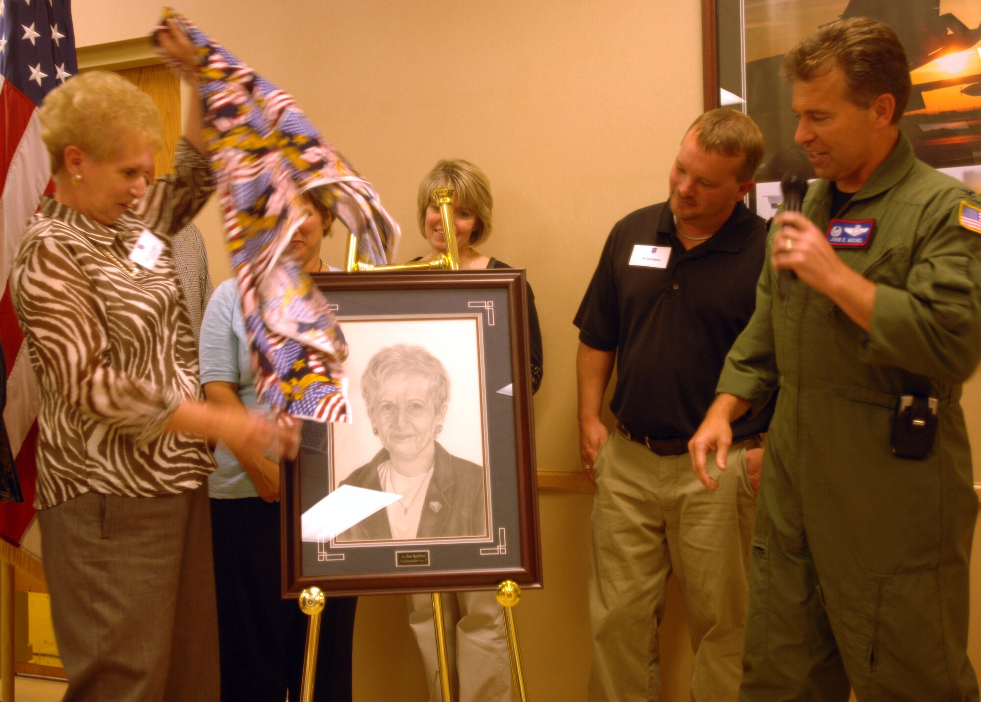 Mrs. Jo Ann Renfrow unveils her portrait during a ceremony naming her as the newest wing ambassador Aug. 27.  Assisting her is Col. John Michel, 319th Air Refueling Wing commander and her family.  Mrs. Renfrow is the seventh person proclaimed a wing ambassador since the program's induction.  Wing ambassadors are business and civic leaders from the local community who have demonstrated outstanding and continual support of the base, its mission and its Airmen.  Ambassadors represent the community and the base during wing events and also during meetings with senior Air Force and political leaders. (U.S. Air Force photo/Tech. Sgt. Joseph Kapinos)