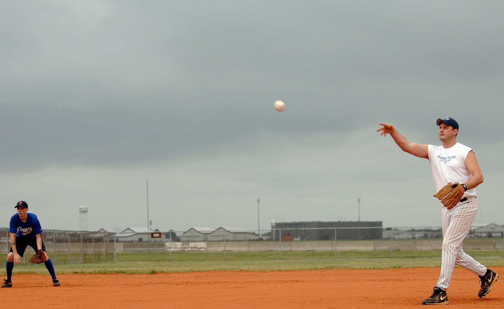 LANGLEY AIR FORCE BASE, Va. -- Tech. Sgt. Thomas Winkler, 1st Communications Squadron, pitches the ball as third baseman Senior Airman Joshua Phillips crouches down during the softball championship game against the 1st Equipment Maintenance Squadron, Aug. 28.  The 1st EMS finished the season unbeaten, but lost to 1st CS in the championship game 18-15.  (U.S. Air Force photo/Senior Airman Vernon Young)