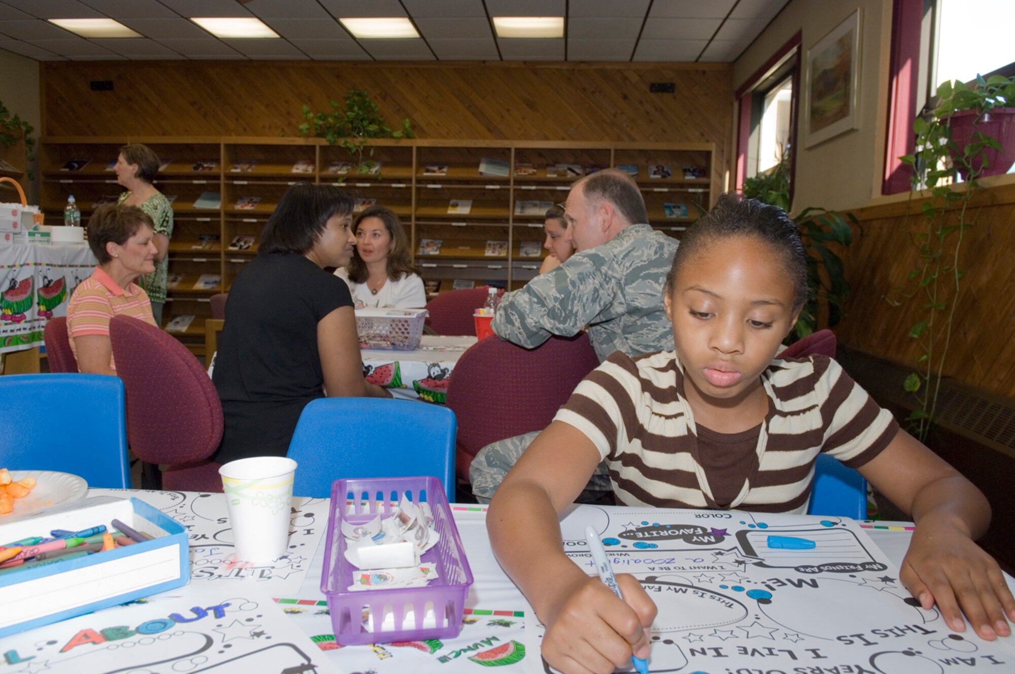 HANSCOM AFB, Mass. -- Nine-year-old Tyra Fisher completes a child activity sheet while spouses of deployed servicemembers talk with Lt. Col.  Gerald Parish, 66th Mission Support Group vice commander, about deployment issues during the Airman and Family Readiness Center's Back to School Hearts Apart gathering, Aug. 27. Hearts Apart events are specifically designed for families of deployed and extended-temporary duty servicemembers. The gatherings allow families to connect during fun events and offer families a forum to discuss deployment-related concerns and issues. To learn more about the program, contact the A&FRC at (781) 377-4222. (U.S. Air Force photo by Rick Berry)