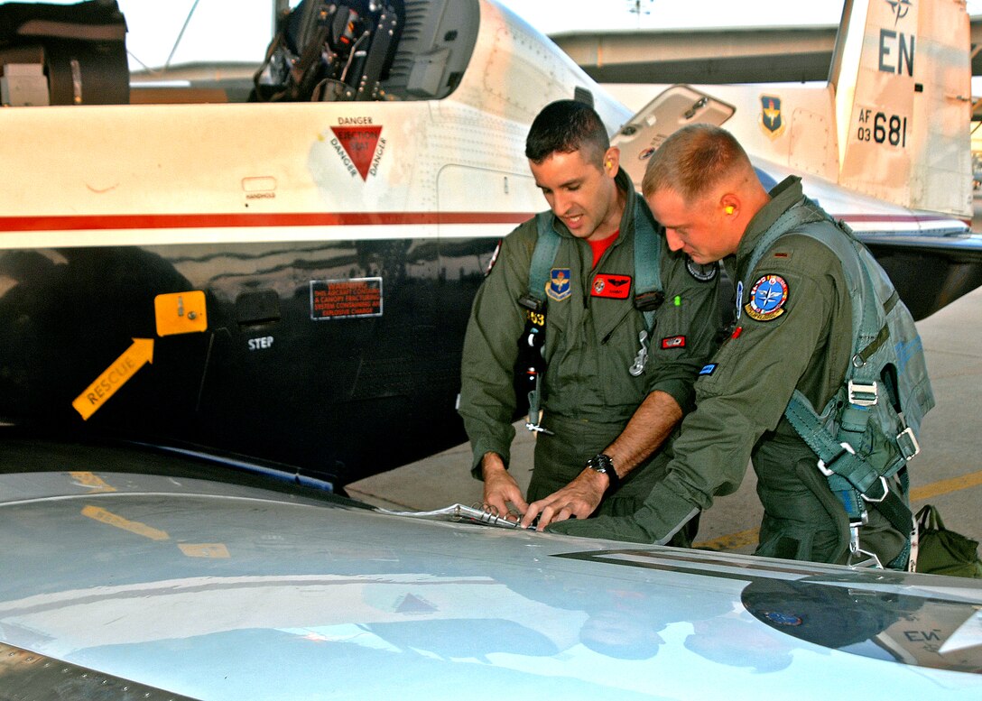 Capt. Chris Breffitt, left, an instructor with the 89th Flying Training Squadron, and student pilot 2nd Lt. Jeremy Curbey go through a pre-flight checklist Aug. 29 as the first class of the Euro-NATO Joint Jet Pilot Training Program took to the air in the T-6A Texan II. The aircraft began arriving in January, and about 70 will replace the program's aging T-37 Tweet fleet. (U.S. Air Force photo/Lou Anne Sledge)