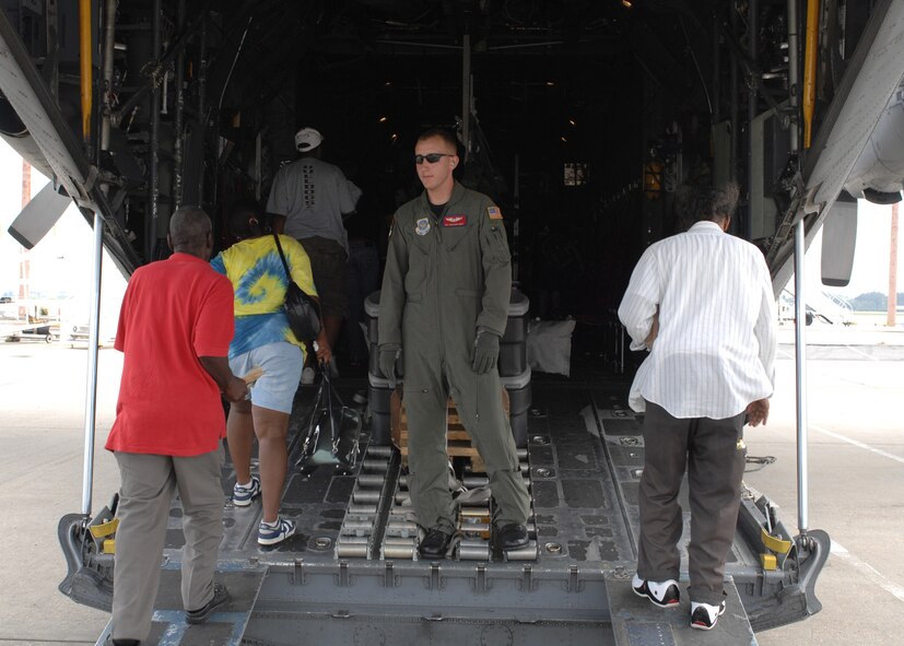 NEW ORLEANS INTERNATIONAL AIRPORT-- Senior Airman Sheldon Cary, a 39th Airlift Squadron loadmaster from Dyess Air Force Base, Texas, directs hurricane evacuees onto a C-130, August 31. Dyess AFB C-130s and aircrews evacuated more than 400 residents that had no other means of transportation to reach a safer area. The evacuees were sent to different cities in Tennessee where relief teams were awaiting their arrival with food, water and shelter. (U.S. Air Force photo/ Senior Airman Jennifer Romig)