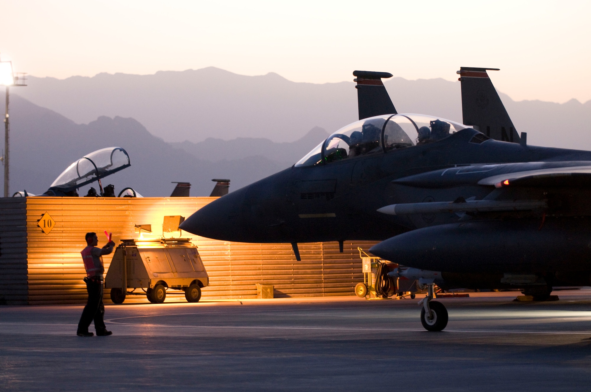 BAGRAM AIR FIELD, Afghanistan -- A crew chief with the 455th Expeditionary Aircraft Maintenance Squadron marshals an F-15E Strike Eagle of the "dawn patrol" here August 27, 2008. The two F-15Es that made up the "dawn patrol" taxied out just as first light began to break over the picturesque mountains of Afghanistan. (U.S. Air Force photo by Staff Sgt. Samuel Morse/Released)