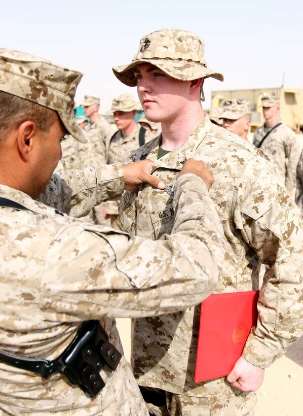 Petty Officer 2nd Class Joseph Collard, a Saco, Maine, native, stands at attention as 3rd Marine Aircraft Wing (Forward) Command Master Chief, Chief Petty Officer Perfecto Cronemeyer, pins a Fleet Marine Force Warfare Specialist badge onto his chest Sept. 2. Collard and five other Navy ATCs earned the badge during this deployment with Marine Air Control Squadron 1, Marine Air Control Group 38, 3rd Marine Aircraft Wing (Forward). (U.S. Marine Corps photo by Lance Cpl. Fredrick J. Coleman) (Released)