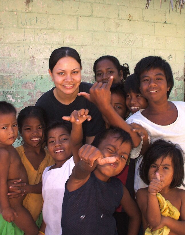 Senior Airman Jennifer White spends time with a group of local Kiribati children. Airman White, 624th Aeromedical Staging Squadron, Hickam Air Force Base, Hawaii, was a part of a PACAF joint forces humanitarian mission to the Republic of Kiribati. (Navy Photo/Petty Officer AC Rainey)