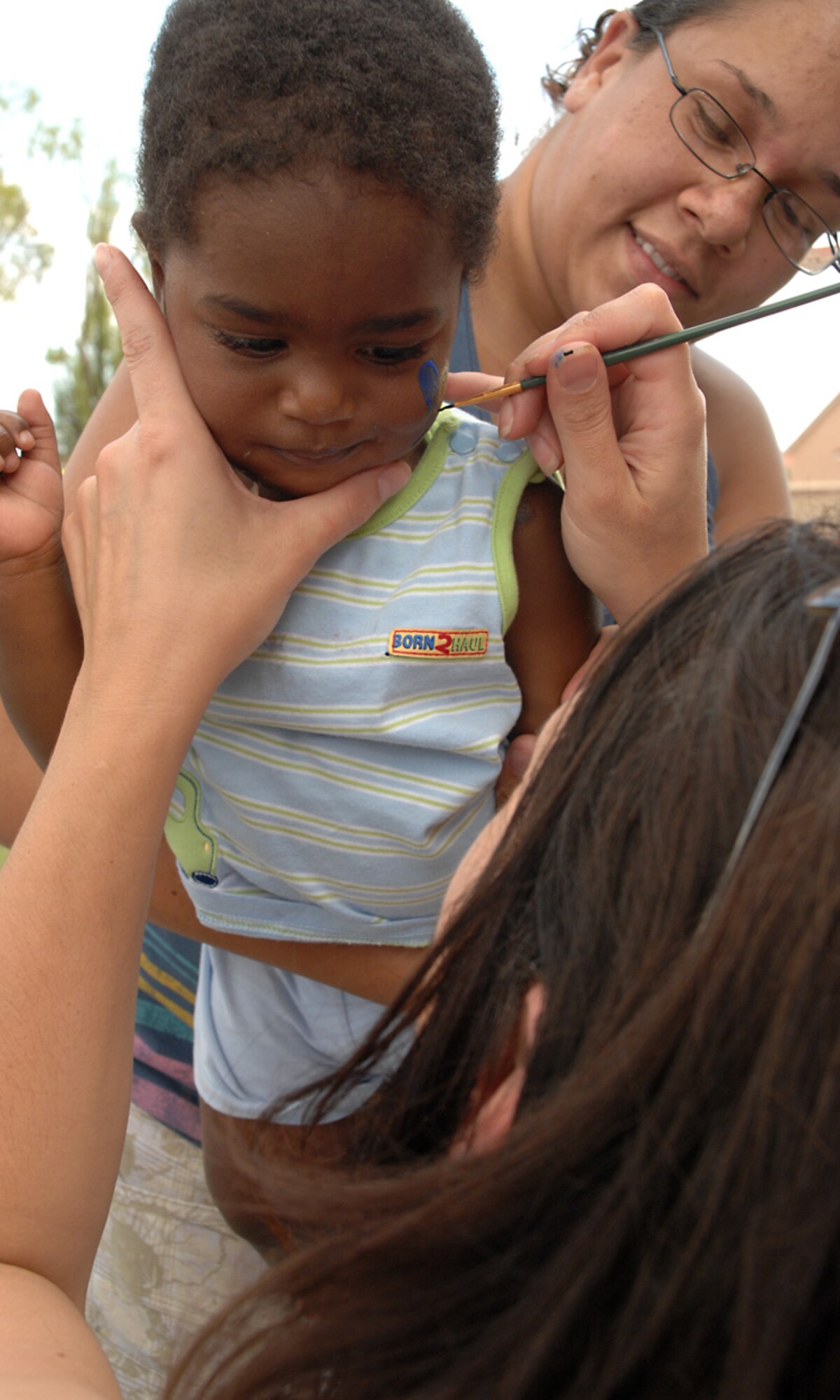 Iduna Dorsey holds Terrell Dorsey, 1, son of Senior Airman Jerome Dorsey, 49th Force Support Squadron, while he has his face painted by Diane Corppetts at the Back to School Kid's Carnival at Holloman Air Force Base, N.M., Aug. 30. (U.S. Air Force photo/ Senior Airman Tiffany Trojca)