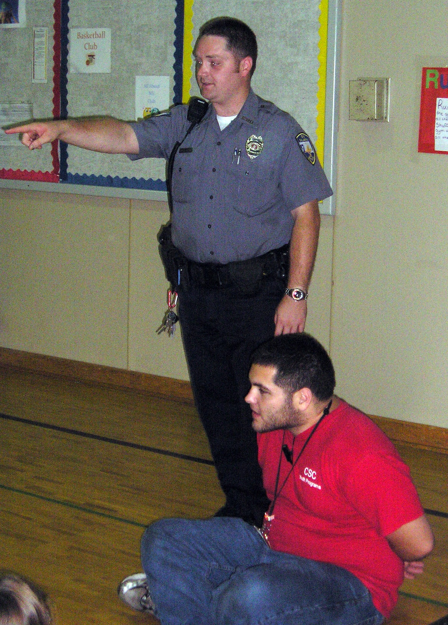 James McFadden, seated, is the subject of a hand-cuffing demonstration by his brother, Enid Police Officer Robert McFadden, during a farewell party Aug. 27. Known to the children at Vance’s School Age Program as “Mr. James,” James McFadden will join his brother on the Enid Police Department after two years as a counselor with the SAP. (Courtesy photo)