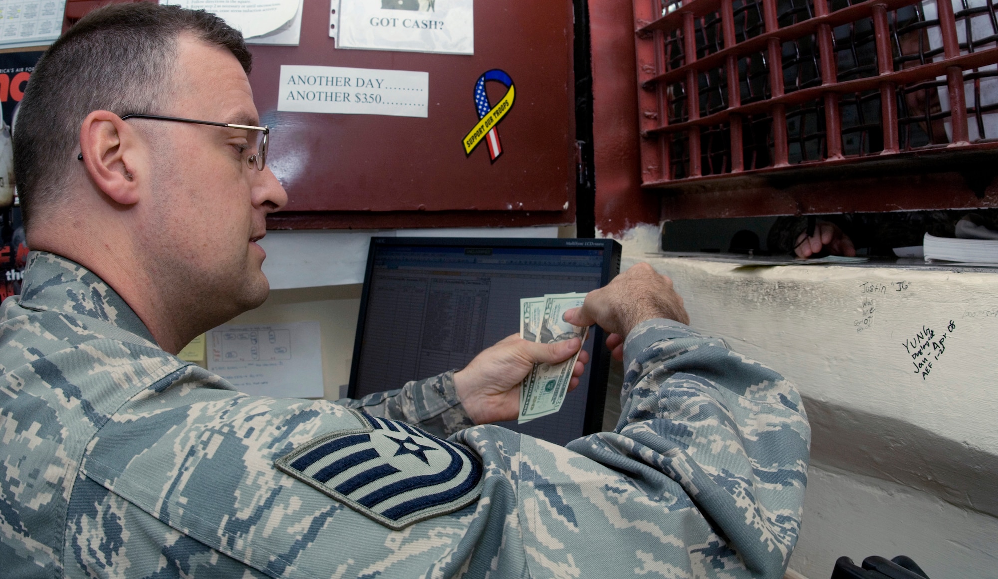 Tech. Sgt. Aaron Levisay disburses cash to a customer who is using her EagleCash card.  Sergeant Levisay is a cashier for the 332nd Air Expeditionary Wing's finance office at Joint Base Balad, Iraq.  He is deployed from the South Dakota Air National Guard's 114th Fighter Wing.  (U.S. Air Force photo/Tech. Sgt. Erik Gudmundson) 