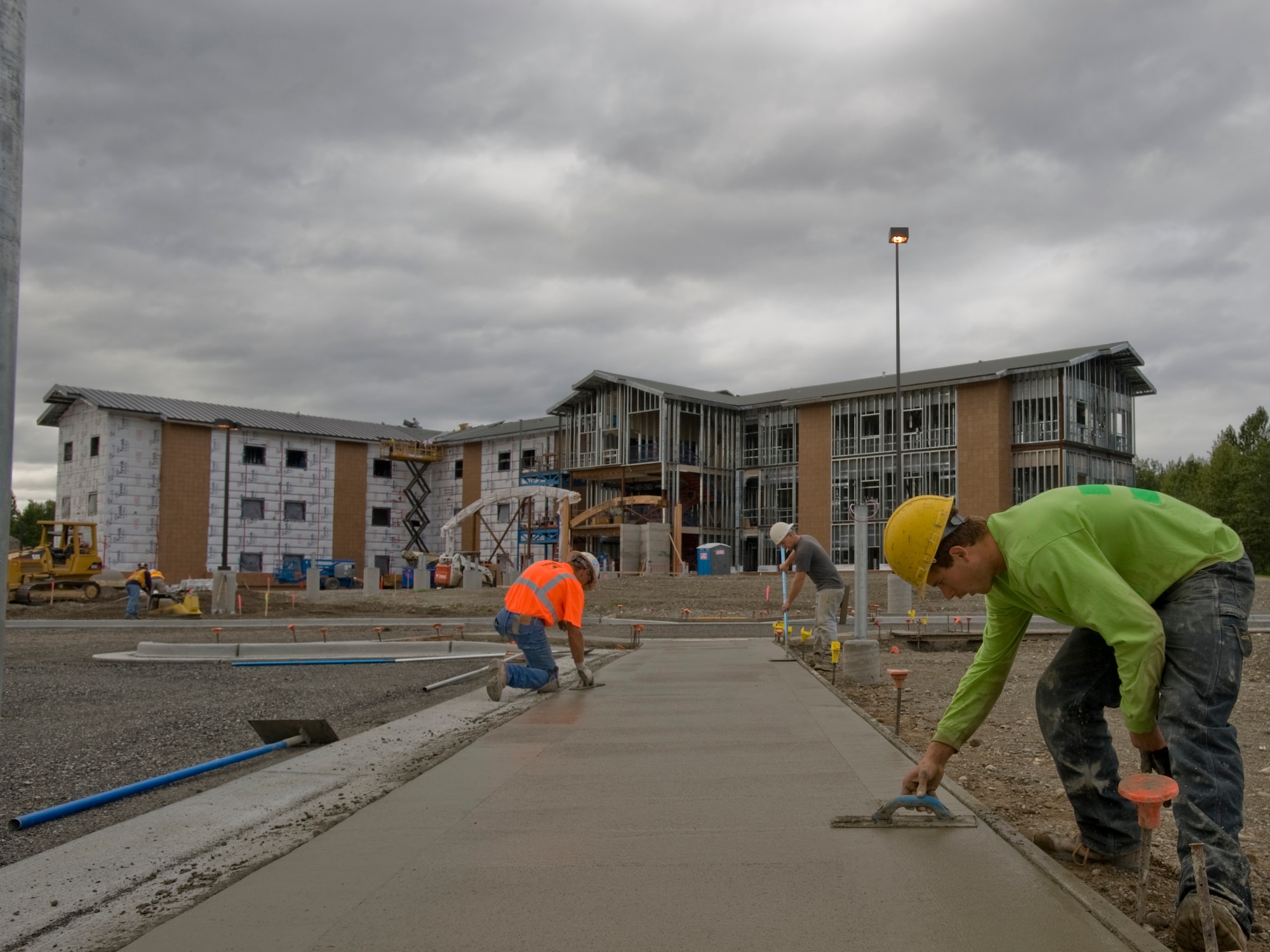 ELMENDORF AIR FORCE BASE, Alaska -- Shannon Simpson and fellow members from Finishing Edge Concrete and Construction, smooth out freshly layed concrete for a sidewalk here Sept. 2. The sidewalk is being constructed alongside the new parking lot for the brand new Airman dorm. The dorm is scheduled to be fully operational by mid-Febuary. (U.S. Air Force photo/Staff Sgt. Joshua Garcia)