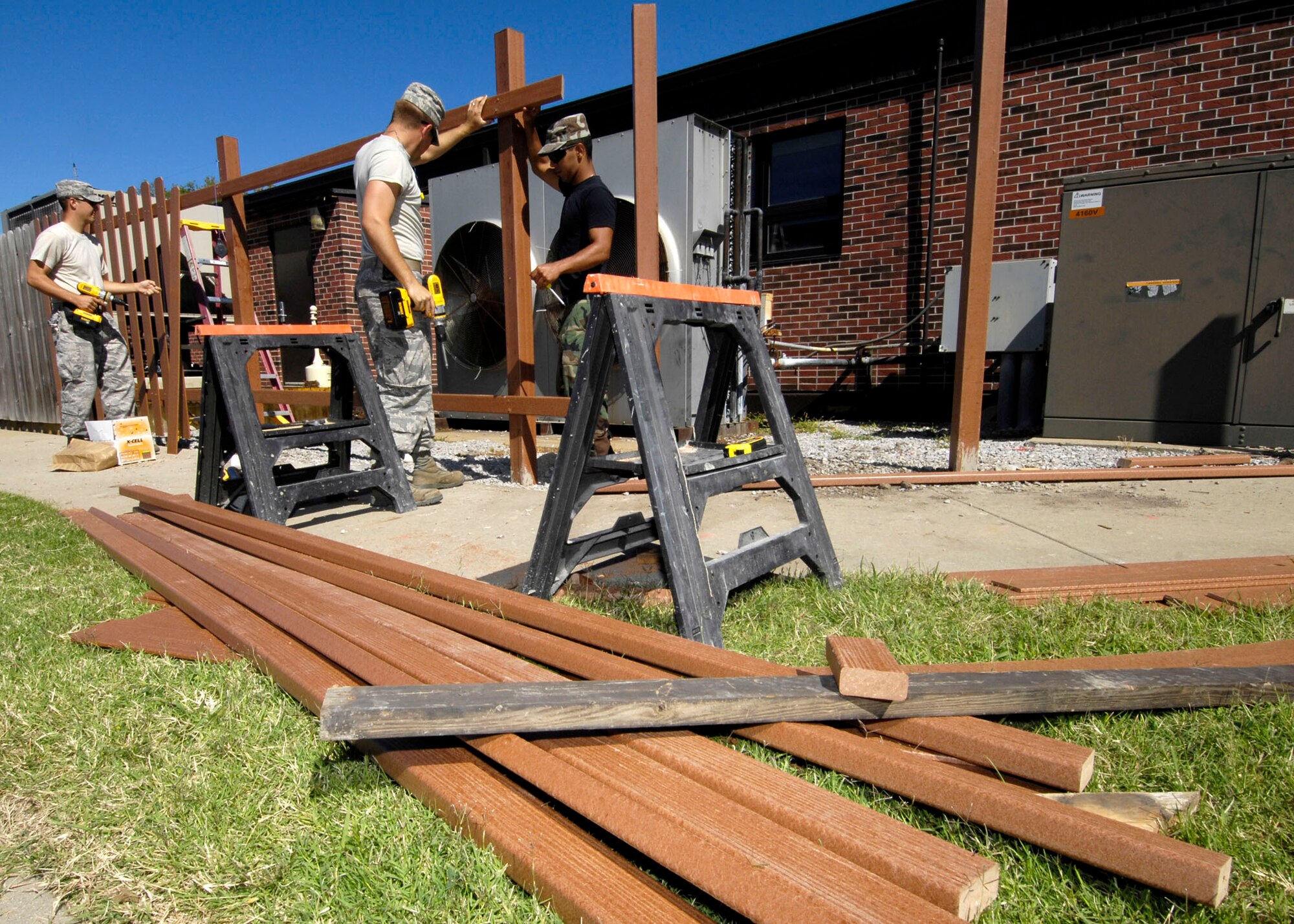 SCOTT AIR FORCE BASE, Ill. -- Airman 1st Class John, 375th Civil Engineering Squadron structural apprentice, and Senior Airman Pedro Mollina, 375th CES structural craftsman, build the foundation for the first "green fence" in front of Building 700, while Staff Sgt. James Messer, 375th CES structural craftsman, drills boards onto the posts. The fence is made of recycled plastic and wheat straw.
(US Air Force photo/Senior Airman Mildred Guevara)

