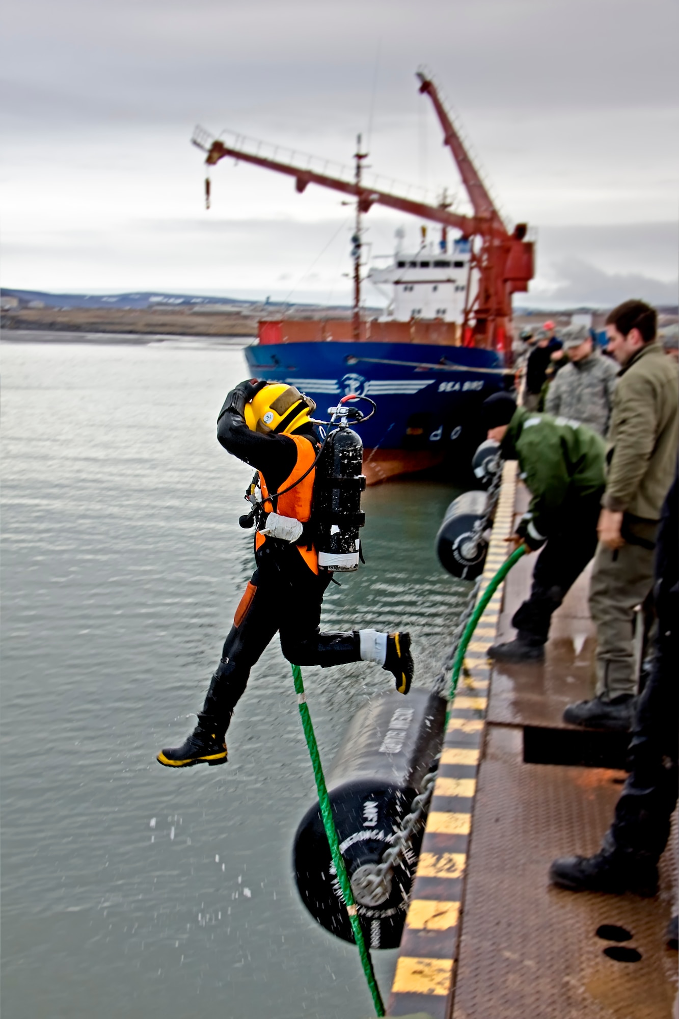 Petty Officer 1st Class Daniel Luberto leaps into the water next to DeLong Pier at Thule Air Base, Greenland to survey underwater debris located 25 feet deep on the ocean floor (U.S. Air Force photo by Master Sgt. Ben Huseman).
