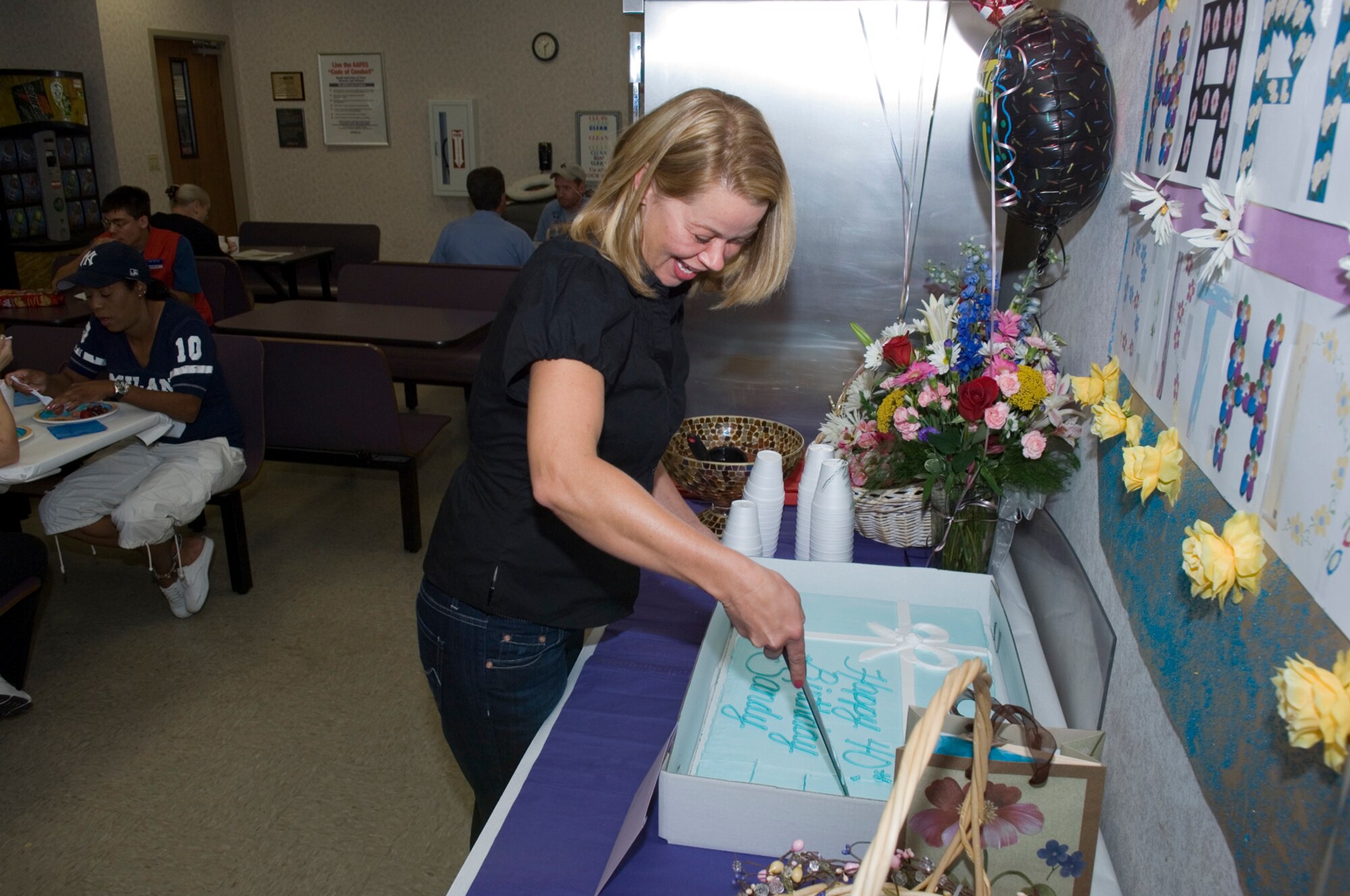 HANSCOM AFB, Mass. - Sandy Nearing cuts her birthday cake during the surprise birthday party her husband, Capt. Louis Nearing, arranged while deployed to the AOR.  The celebration was held Aug. 29 at the Commissary, where Mrs. Nearing works.  (U.S. Air Force photo by Rick Berry)
