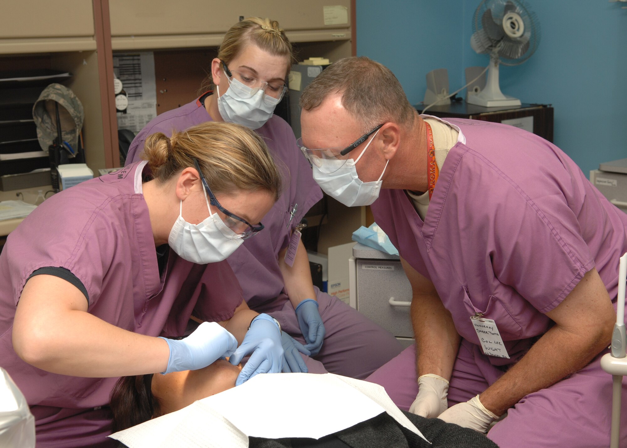 SPANGDAHLEM AIR BASE, Germany – Col. Lee Wight, 52nd Fighter Wing Commander, watches Capt. Christina Sheets, 52nd Dental Squadron Dentist as she assists a patient while participating in the commander shadow program with Senior Airman Bridgit Borseth, dental assistant 52nd Dental Squadron, 52nd Fighter Wing.  During the CC shadow program the CC shadows an Airman while the Airman performs the daily job.  (U.S. Air Force photo by Airman 1st Class Allen Pollard)
