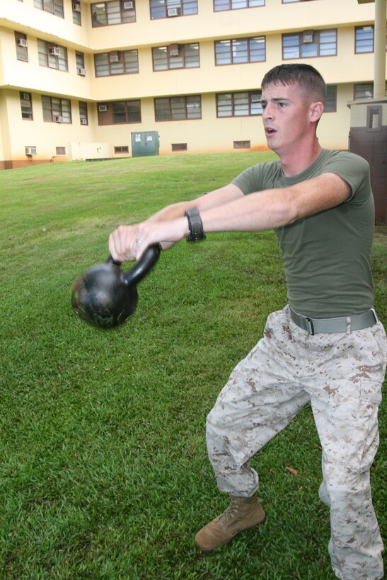 Pfc. Scott James demonstrates a kettle bell swing Sep. 4 at the U.S. Marine Corps Forces, Pacific, Headquarters building. The kettle bell swing is designed to  prepare him for the Combat Fitness Test, which takes effect Oct. 1. James is an accounting manager for Customer Liaison Services, MarForPac.