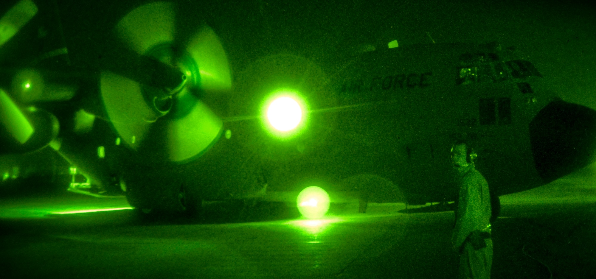 A C-130 Hercules starts its engines in the early morning Sept. 2 as Airman 1st Class Delmar Karnes, the loadmaster, keeps a watchful eye down the flight line at Baghdad International Airport, Iraq.  (U.S. Air Force photo/Tech. Sgt. Erik Gudmundson)
