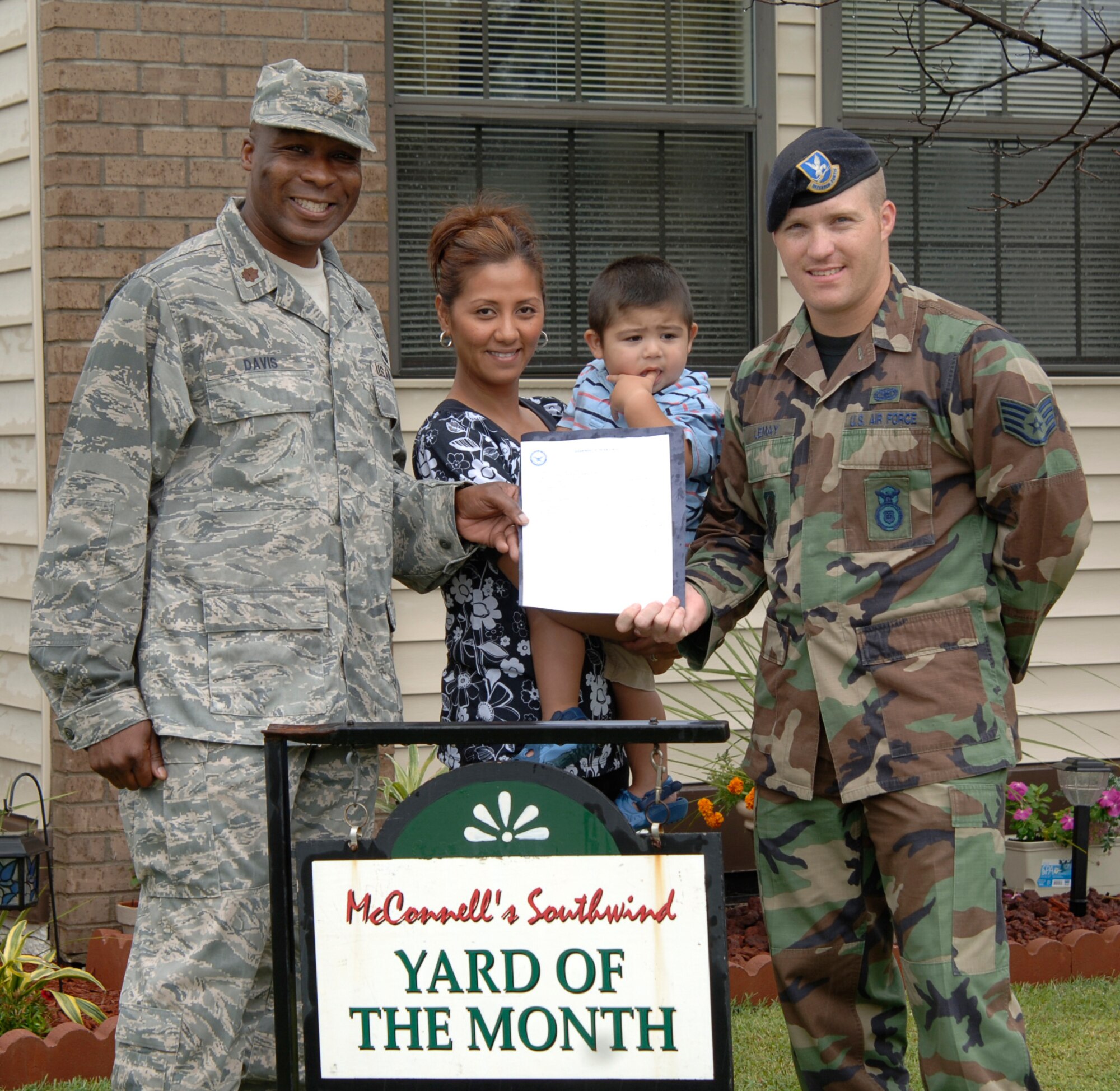 MCCONNELL AIR FORCE BASE, Kan. -- Maj. James Davis, 22nd Mission Support Group deputy commander recognizes Staff Sgt. Matthew LeMay, 22nd Security Forces Squadron, along with wife Maryjane and son Jayden, age 1, for winning the yard of the month, Sept. 02. The Jackson family won yard of the month for August. (Photo by Senior Airman Roy Lynch)