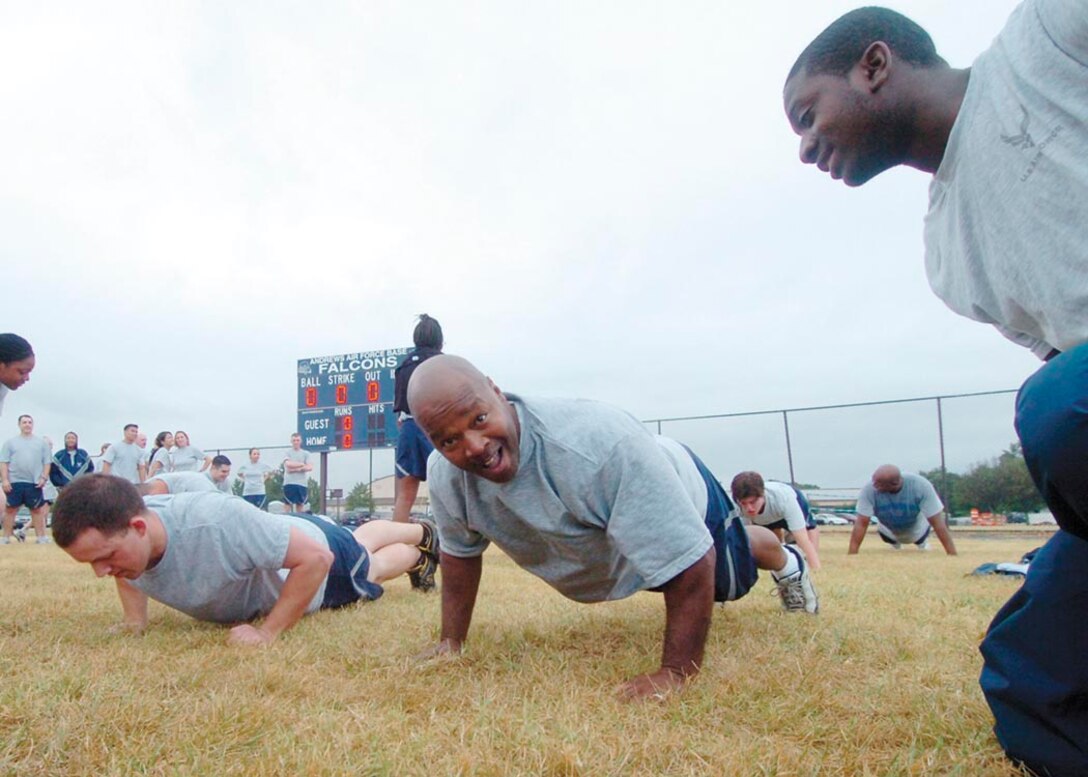 Master Sgt. Anthony Campbell, 579th Dental Squadron, Dental Lab NCOIC, second from left, calls cadence during a push-up and sit-up competition on the softball field near the West Fitness Center Aug. 29. Approximately 700 members from the 79th Medical Wing participated in the day-long athletic event, which consisted of a two-mile walk/run,  the push-up and sit-up contest, softball, basketball, volleyball, tug-of-war and slueshing competitions. The purpose of the event was to foster Esprit de corps among fellow Airmen within the 79th and 579th Medical Groups. (U.S. Air Force photo by Bobby Jones)