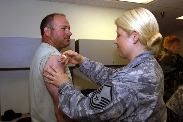 MINOT AIR FORCE BASE, N.D. — Master Sgt. James Fisher, 5th Aircraft Maintenance Squadron, aircraft section chief, receives a shot from Master Sgt. Michelle Dunn, 5th Medical Operations Squadron primary care flight chief, during the Installation Personnel Readiness Element pre-deployment briefing here Aug. 28. The IPRE process requires Airmen to obtain all necessary inoculations prior to deploying. (U.S. Air Force photo by Airman 1st Class Jesse Lopez)