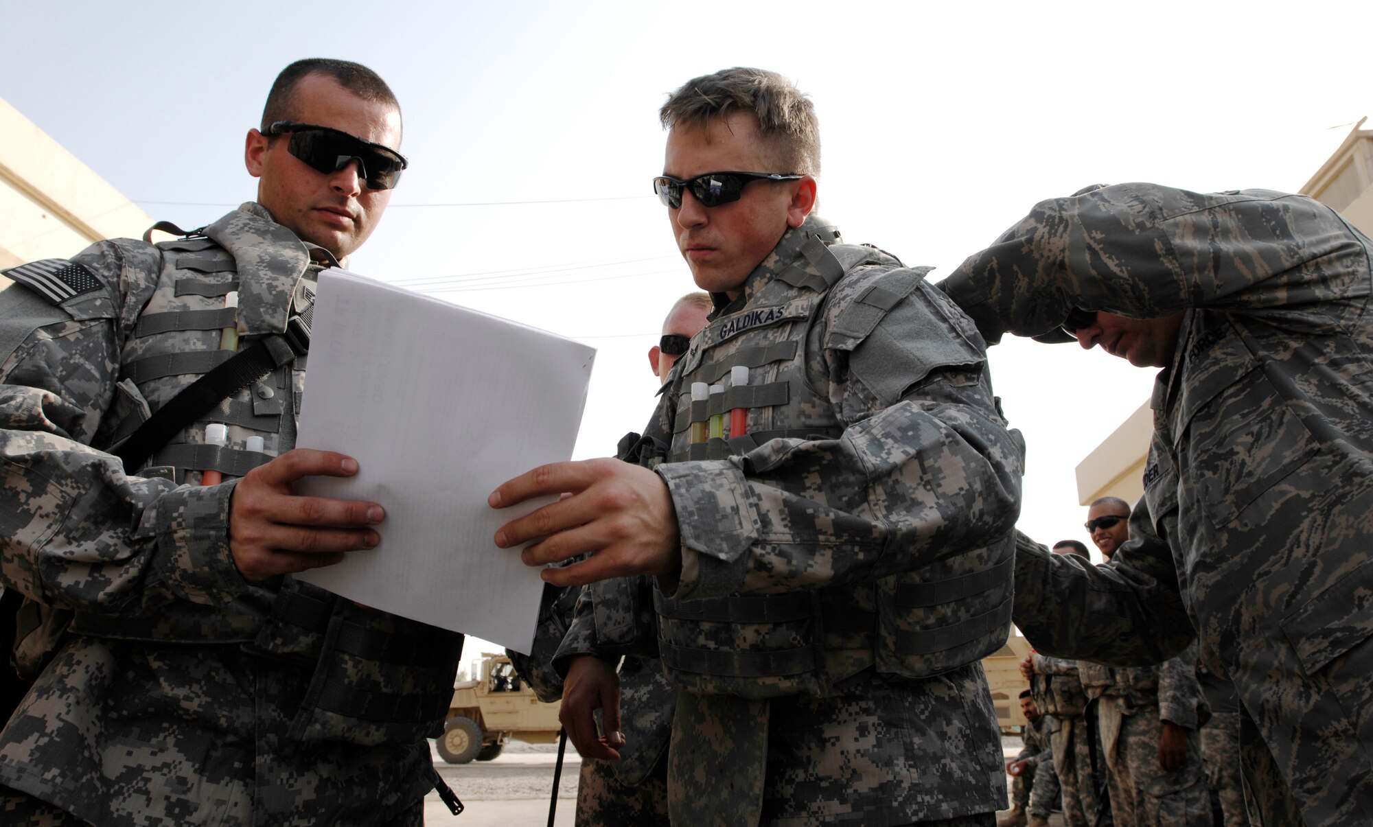 JOINT BASE BALAD, Iraq --Staff Sgt. Joseph Webb (left) and Senior Airman Jeffrey Galdikas (middle) verify information while Senior Master Sgt. Garry Souder (right) adjusts Airman Galdikas' body armor here Sept. 4. Webb, Galdikas and Souder are assigned to the 732nd Expeditionary Civil Engineer Squadron Utilities Detachment 6. The 732nd ECES is just one component of the 732 Air Expeditionary Group, which provides joint source solution Airmen from numerous Air Force specialties to meet Army, Navy and Marine Corps mission requirements. Webb is deployed from Elmendorf Air Force Base, Alaska, and his hometown is North Pole, Alaska. Galdikas is deployed from Hickam Air Force Base Hawaii, and his hometown is Chicago. Souder is deployed from Yokota Air Base, Japan, and his hometown is Las Vegas. (U.S. Air Force photo/Airman 1st Class Jason Epley)