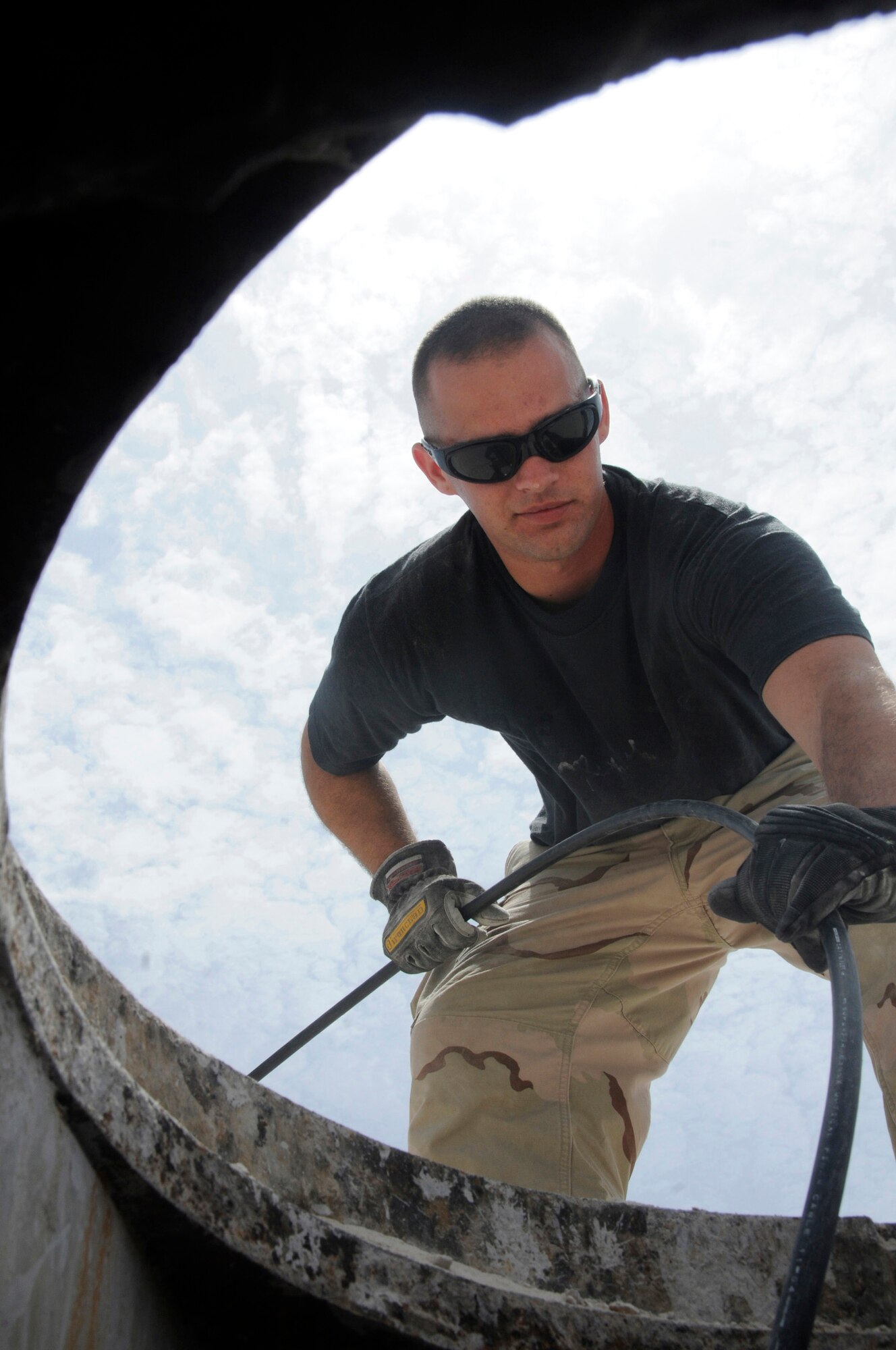 Senior Airman Shawn Buelow, cable and antenna maintenance journeyman assigned to the 379th Expeditionary Communication Squadron, feeds fiber optic cables into a manhole to provide communications for a new facility Sept 3, 2008, at an undisclosed air base in Southwest Asia. Airman Buelow, a native of Kalamazoo, Mich., is deployed in support of Operations Iraqi Freedom, Enduring Freedom and Joint Task Force-Horn of Africa from Wright-Patterson Air Force Base, OH. (U.S. Air Force photo by Staff Sgt. Darnell T. Cannady)