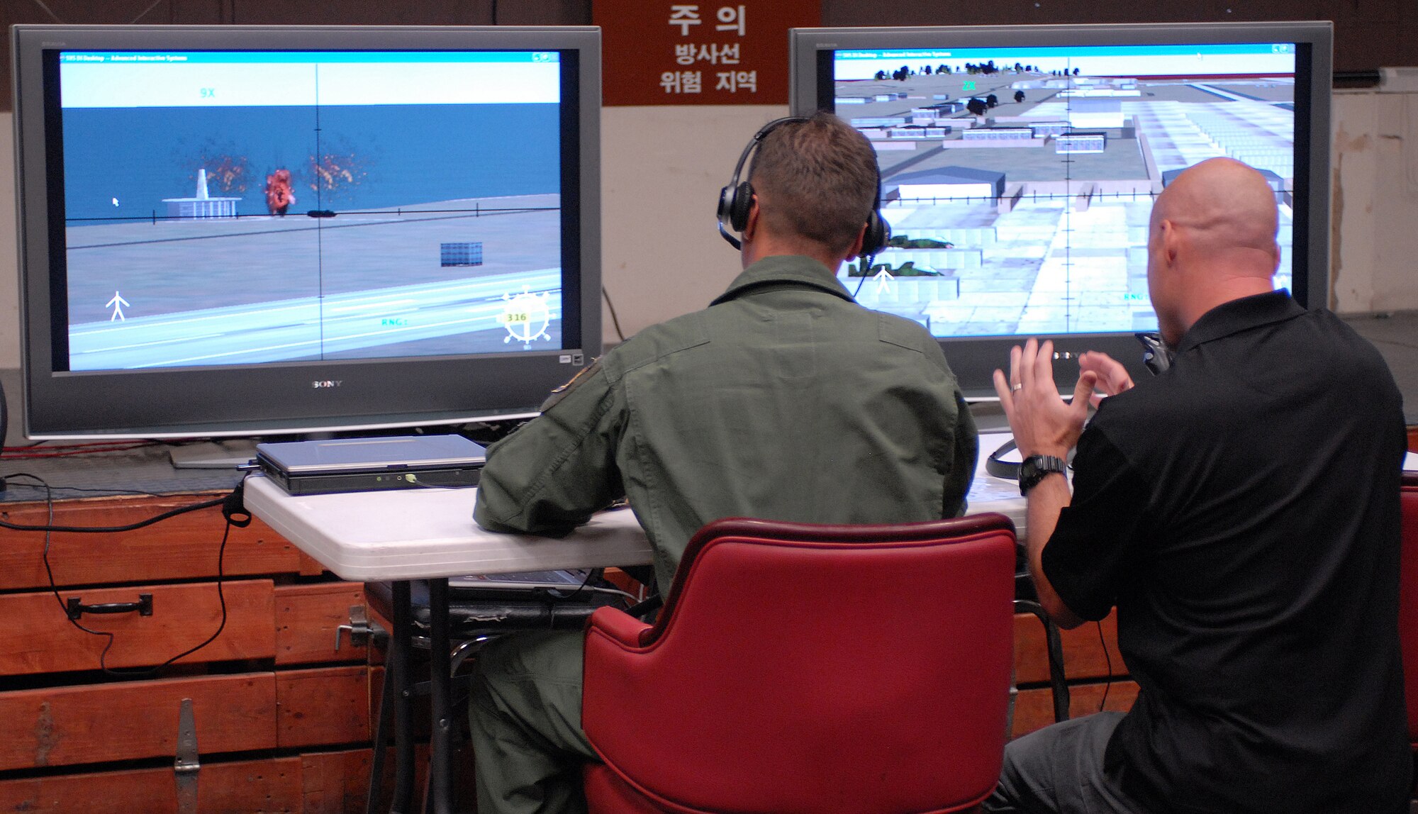 Colonel Bryan "wolf" Bearden, 8th Fighter Wing commander, is assisted by Eric Sheldon, an AC-130 simulator contractor, as he checks out the AC-130 simulator here Aug. 18. AC-130 instructors and contractors brought the simulator here from Hurlburt Field, Fla. to teach 8th Securty Forces Squadron members how to talk to the aircrews and call for air support. (U.S. Air Force photo/Senior Airman Gustavo Gonzalez) 