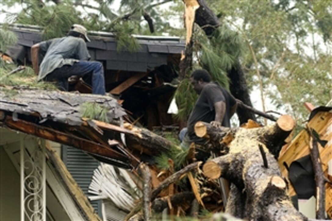 Leonard Cato, left, and friend Steve Marshall, work to clear Cato's niece's home of a fallen tree during the cleanup after Hurricane Gustav in Baton Rouge, La., Sept. 3, 2008