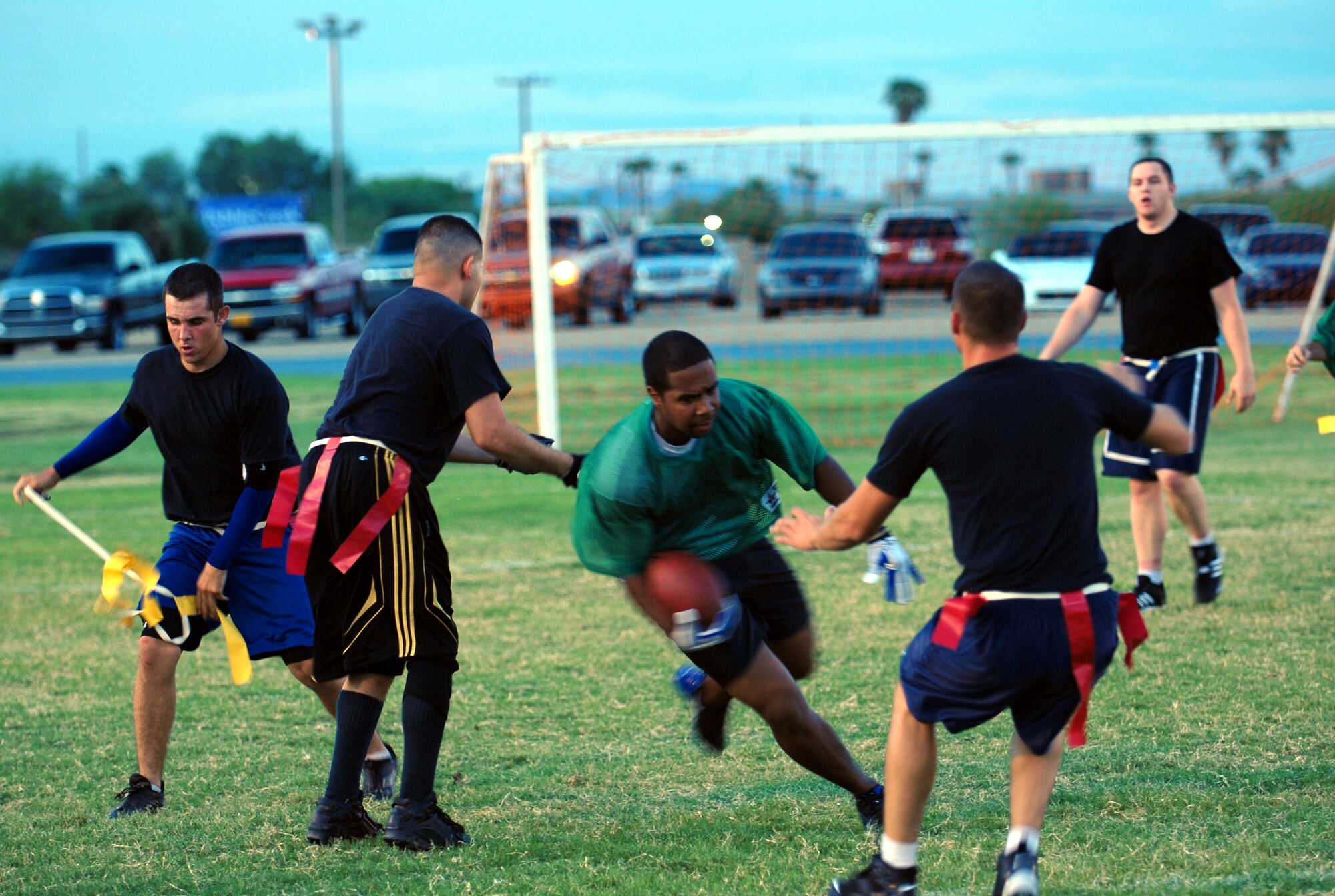 Titus Butcher, 56th Comptroller Squadron, playing on the joint 56th Mission Support Squadron and 56th Services Squadron team, finishes a 10-yard run as a 61st Aircraft Maintenance Unit team member takes his flag during an intramural flag football game Aug. 26. The joint team won 19-16.