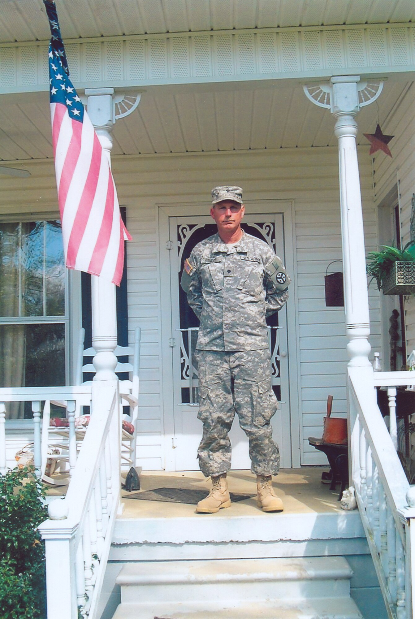 Arnold Engineering Development Center's Jody Frame, in uniform, stands tall on the porch of his home. Frame, who recently joined the Army National Guard, is Aerospace Testing Alliance's  (ATA) supervisor for utility maintenance (except electricity) at Arnold, ATA is the support contractor for the base. (Photo provided)