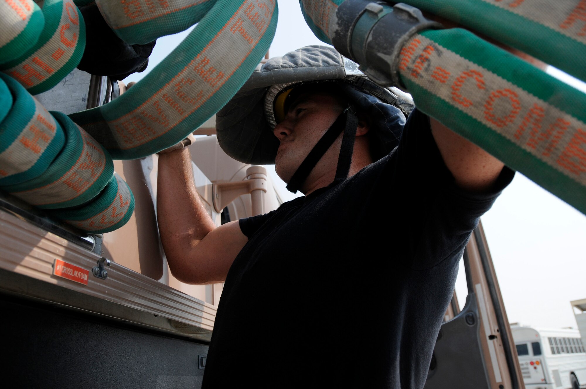 Senior Airman Jeffrey Price, a 379th Expeditionary Civil Engineer Squadron firefighter at an air base in Southwest Asia, reloads the hoses after a successful training exercise Aug. 29. (U.S. Air Force photo/Tech. Sgt. Michael Boquette)