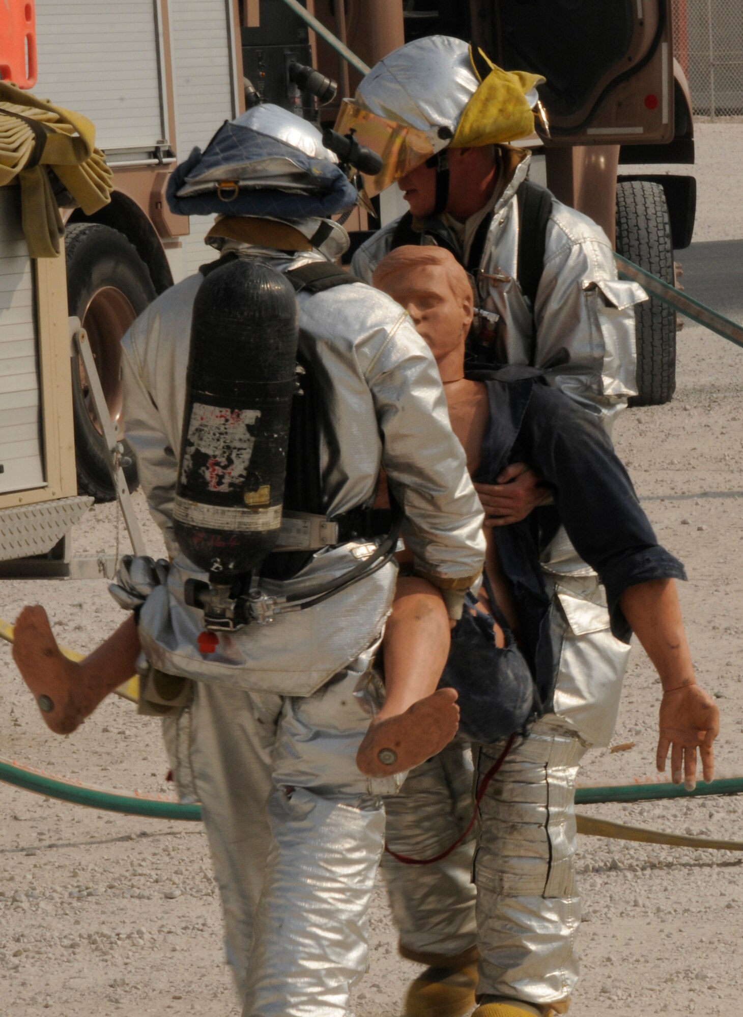 Staff Sgt. Benjamin King (left) and Airman 1st Class Neal Krysinski, 379th Expeditionary Civil Engineer Squadron firefighters at an air base in Southwest Asia, carry a dummy "victim" out of a smoke-filled structure during an exercise Aug. 29.  the firefighters swept the facility for personnel, provided aid to any found inside, extinguished the fire and cleared the building of smoke. Sergeant King is deployed from Seymour Johnson Air Force Base, N.C., and Airman Krysinski is from MacDill AFB, Fla. (U.S. Air Force photo/Tech. Sgt. Michael Boquette)