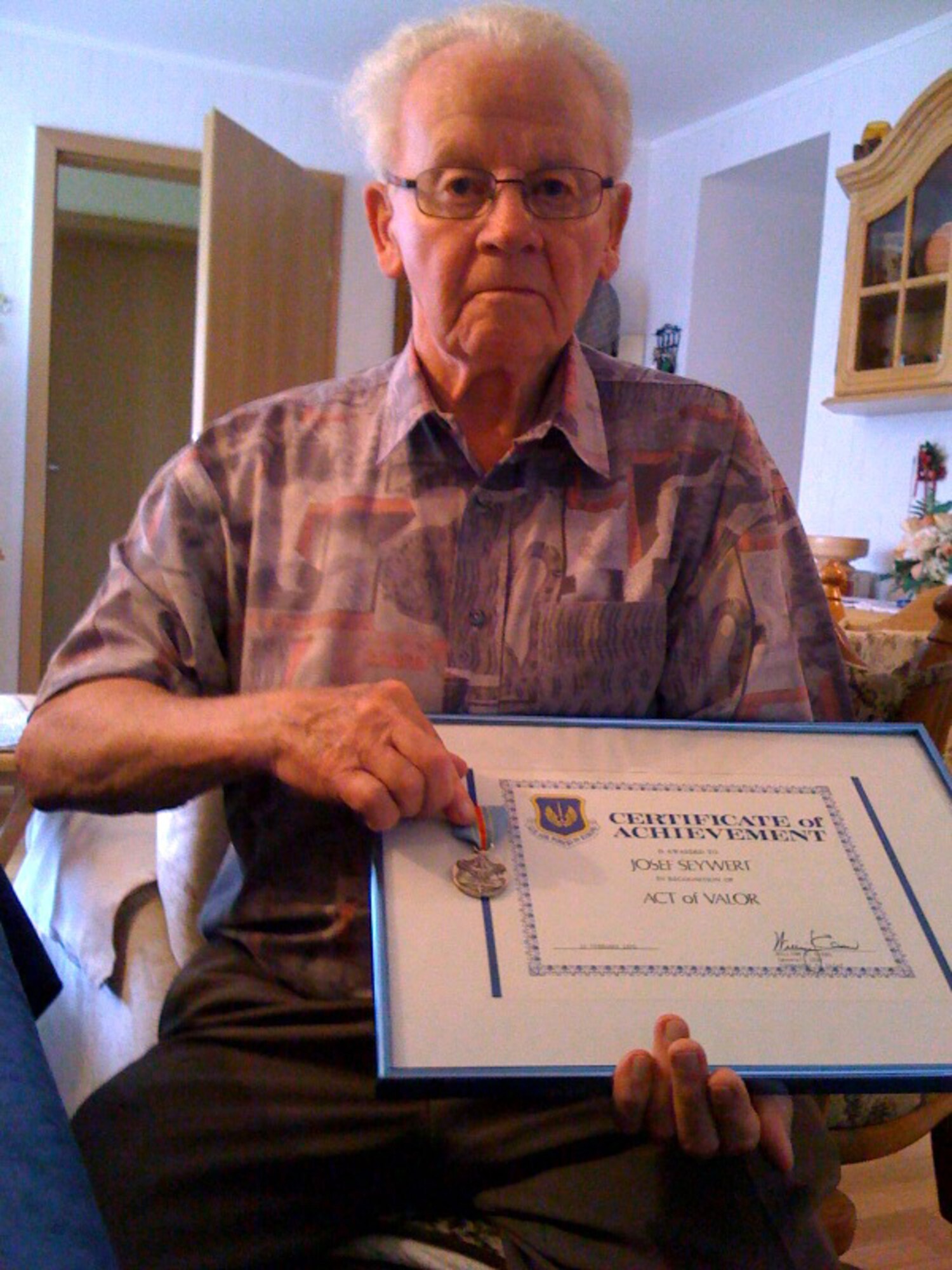 Josef Seywert poses with his Certificate of Achievement for his Act of Valor from Washington D.C. and his medal in his house not far from Spangdahlem Air Base. (U.S. Air Force photo by Senior Airman Clay Murray)