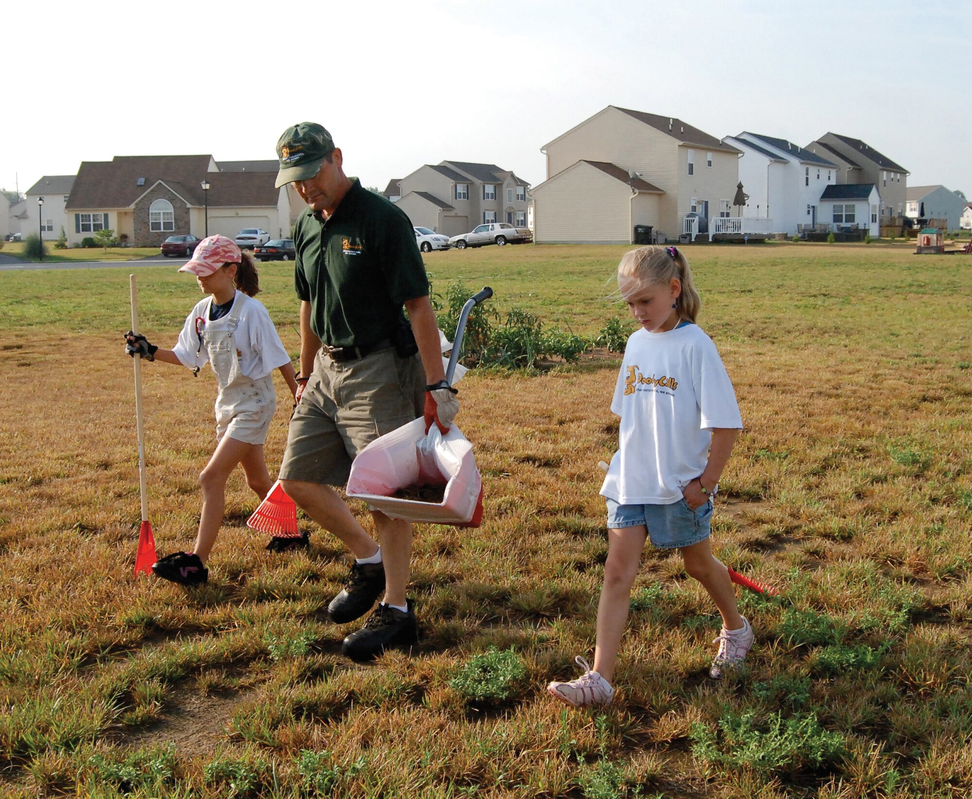 Master Sgt. Don Meyer, 709th Airlift Squadron first sergeant, slowly scans a yard for "golden nuggets" with the help of his 11 and 8-year-old daughters, Leia and Elle. Sergeant Meyer is a franchise owner of DoodyCalls, a nationwide pet waste removal service. (U.S. Air Force photo/Staff Sgt. Steve Lewis)   