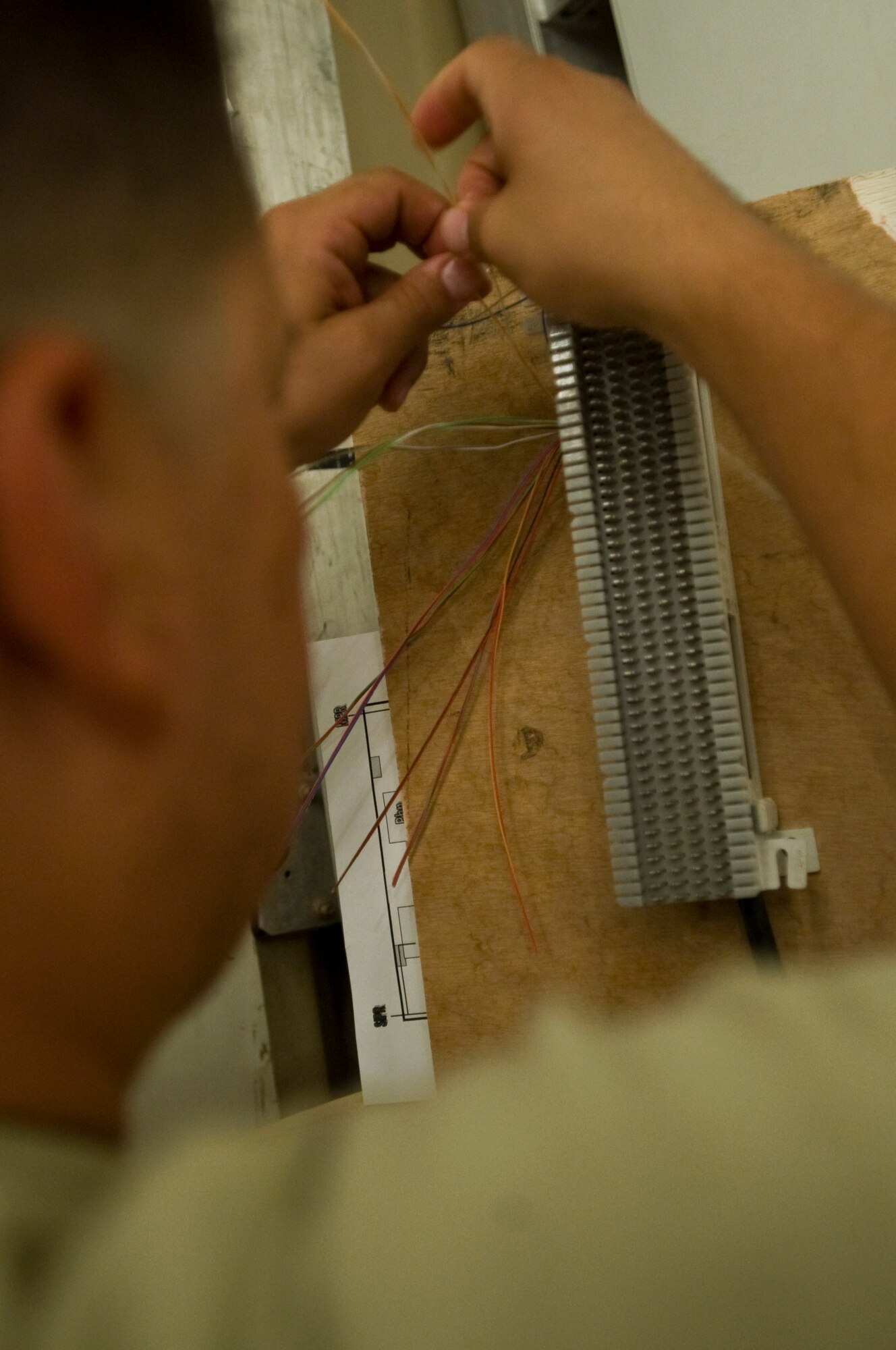 ALI BASE, Iraq -- Staff Sgt. Javiel Ladines, 407th Expeditionary Communications Squadron network technician, separates wires that will be inserted into a cross connector enabling a phone connection Aug. 8, 2008. The 407th ECS "Wire Dogs" installed fiber optics inside a new building that the Navy will use. By installing the fiber optics, they are giving telephone and Internet connections to the Navy which enables them to continue their mission during transitions. Sergeant Ladines is deployed from Tinker Air Force Base, Okla. (U.S. Air Force photo/Airman 1st Class Christopher Griffin)