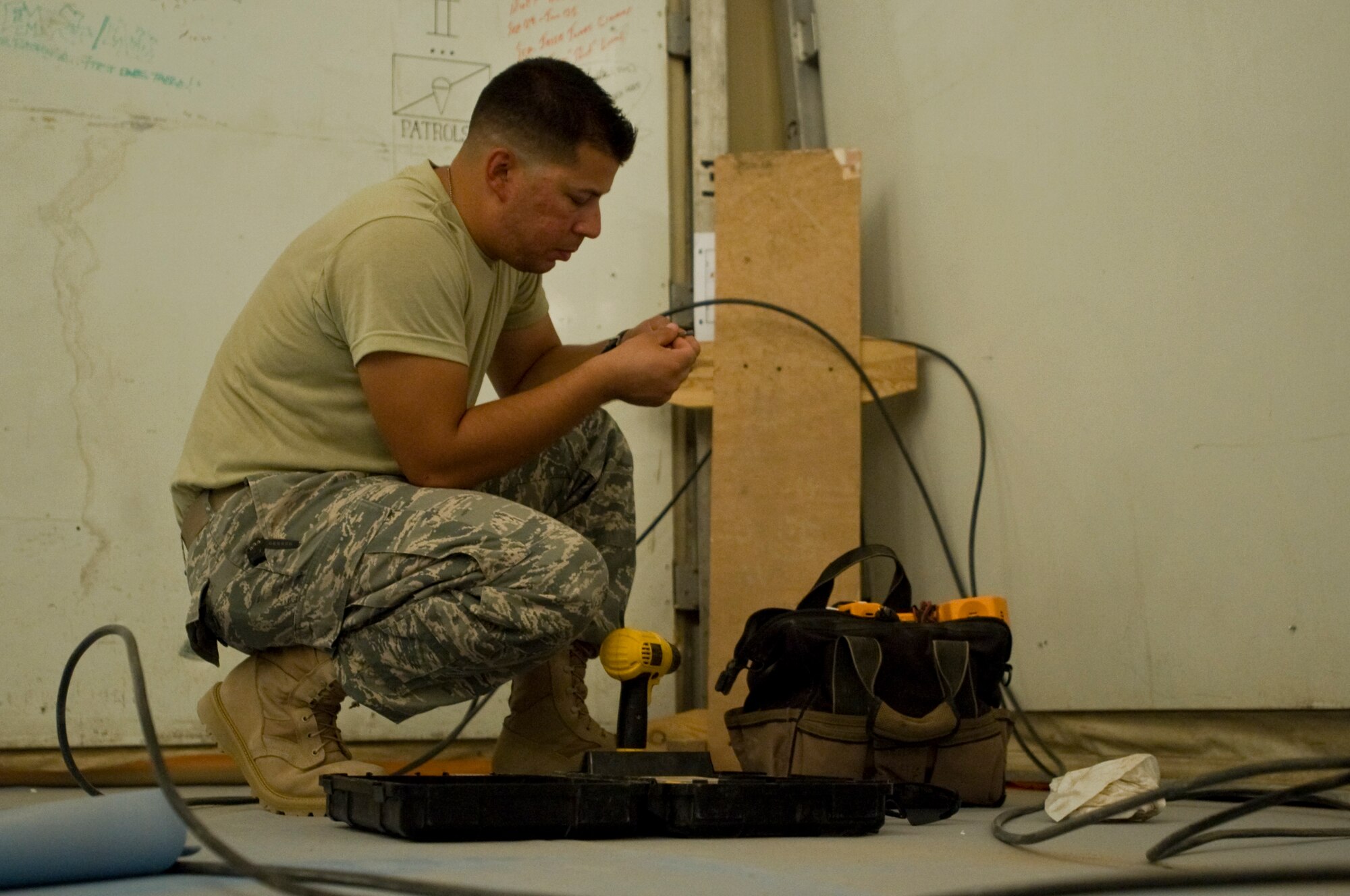 ALI BASE, Iraq -- Staff Sgt. Javiel Ladines, 407th Expeditionary Communications Squadron network technician, strips insulation off of wires to be used for a phone connection Aug. 8, 2008. The 407th ECS "Wire Dogs" installed fiber optics inside a new building that the Navy will use. By installing the fiber optics, they are giving telephone and Internet connections to the Navy which enables them to continue their mission during transitions. Sergeant Ladines is deployed from Tinker Air Force Base, Okla. (U.S. Air Force photo/Airman 1st Class Christopher Griffin)