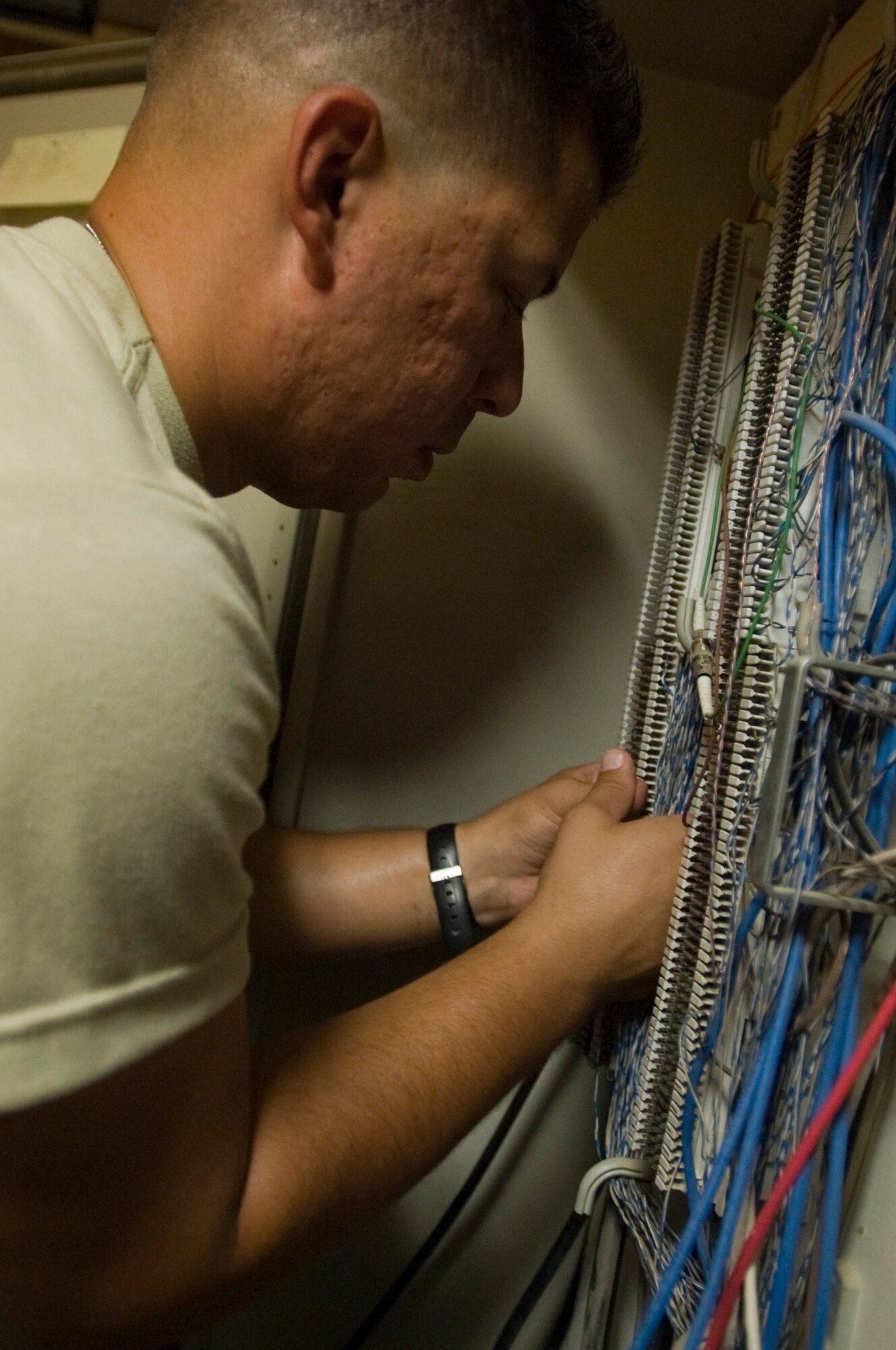 ALI BASE, Iraq -- Staff Sgt. Javiel Ladines, 407th Expeditionary Communications Squadron network technician, separates wires that will be inserted into a cross connector enabling a phone connection Aug. 8, 2008. The 407th ECS "Wire Dogs" installed fiber optics inside a new building that the Navy will use. By installing the fiber optics, they are giving telephone and Internet connections to the Navy which enables them to continue their mission during transitions. Sergeant Ladines is deployed from Tinker Air Force Base, Okla. (U.S. Air Force photo/Airman 1st Class Christopher Griffin)