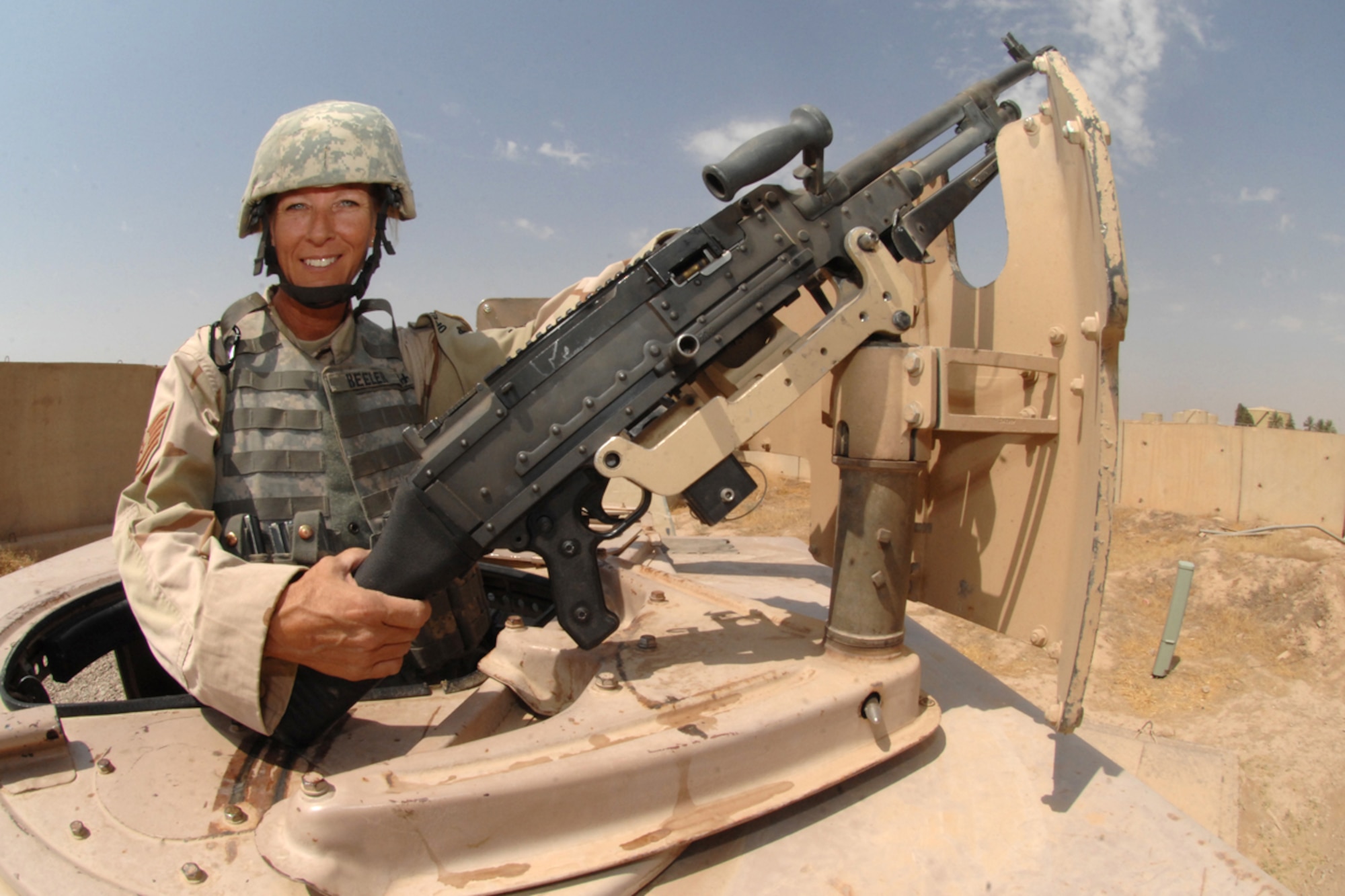 KIRKUK REGIONAL AIR BASE, Iraq -- Tech. Sgt. Kelly Beeler, 506th Expeditionary Security Forces Squadron fire team leader, poses next to an M-240 in the turret of a Humvee Aug. 1.  Sergeant Beeler is the sister of Tech. Sgt. Kimberly McBride and mother of SrA Benjamin Hathaway, 506 ESFS.  The three are deployed here together from Maxwell Air Force Base, Ala., and Schriever AFB, Colo. (U.S. Air Force photo/Senior Airman Randi Flaugh)
