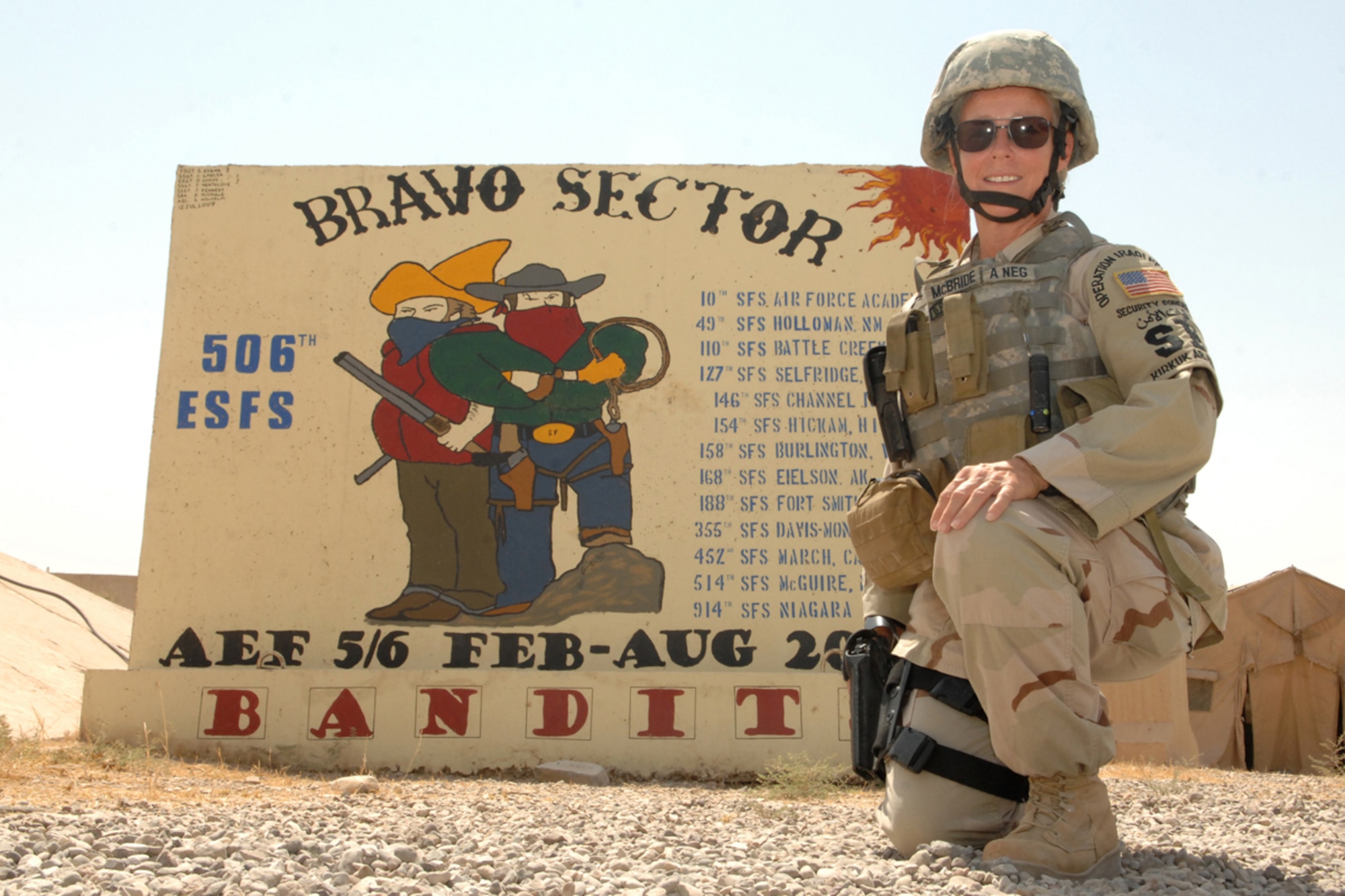 KIRKUK REGIONAL AIR BASE, Iraq -- Tech. Sgt. Kimberly McBride, 506th Expeditionary Security Forces Squadron, poses in front of the Bravo Sector mural here Aug. 1.  Sergeant McBride is the sister of Tech. Sgt. Kelly Beeler and aunt of SrA Benjamin Hathaway, 506 ESFS.  The three are deployed here together from Maxwell Air Force Base, Ala., and Schriever AFB, Colo. (U.S. Air Force photo/Senior Airman Randi Flaugh)
