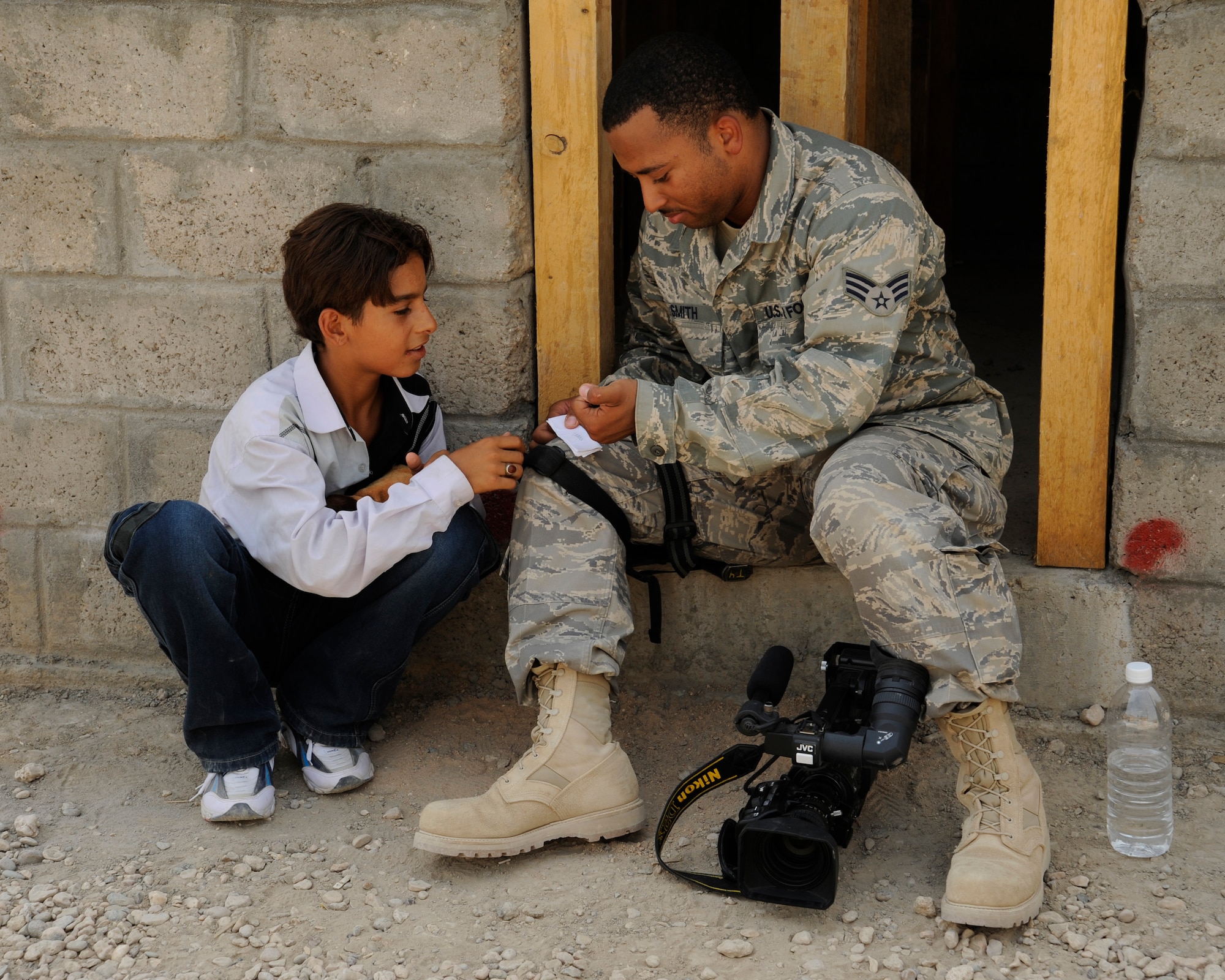 HAWR RAJAB, IRAQ -- Senior Airman Robert Smith, broadcaster with U.S. Air Forces Central - Baghdad Media Outreach Team, shows an Iraqi boy how to write his name in English at Hawr Rajab, Iraq on Aug. 28. Smith, a Chicago native, is deployed from the 375th Airlift Wing, Scott Air Force Base, Ill. (U.S. Air Force photo/Staff Sgt. Paul Villanueva II)