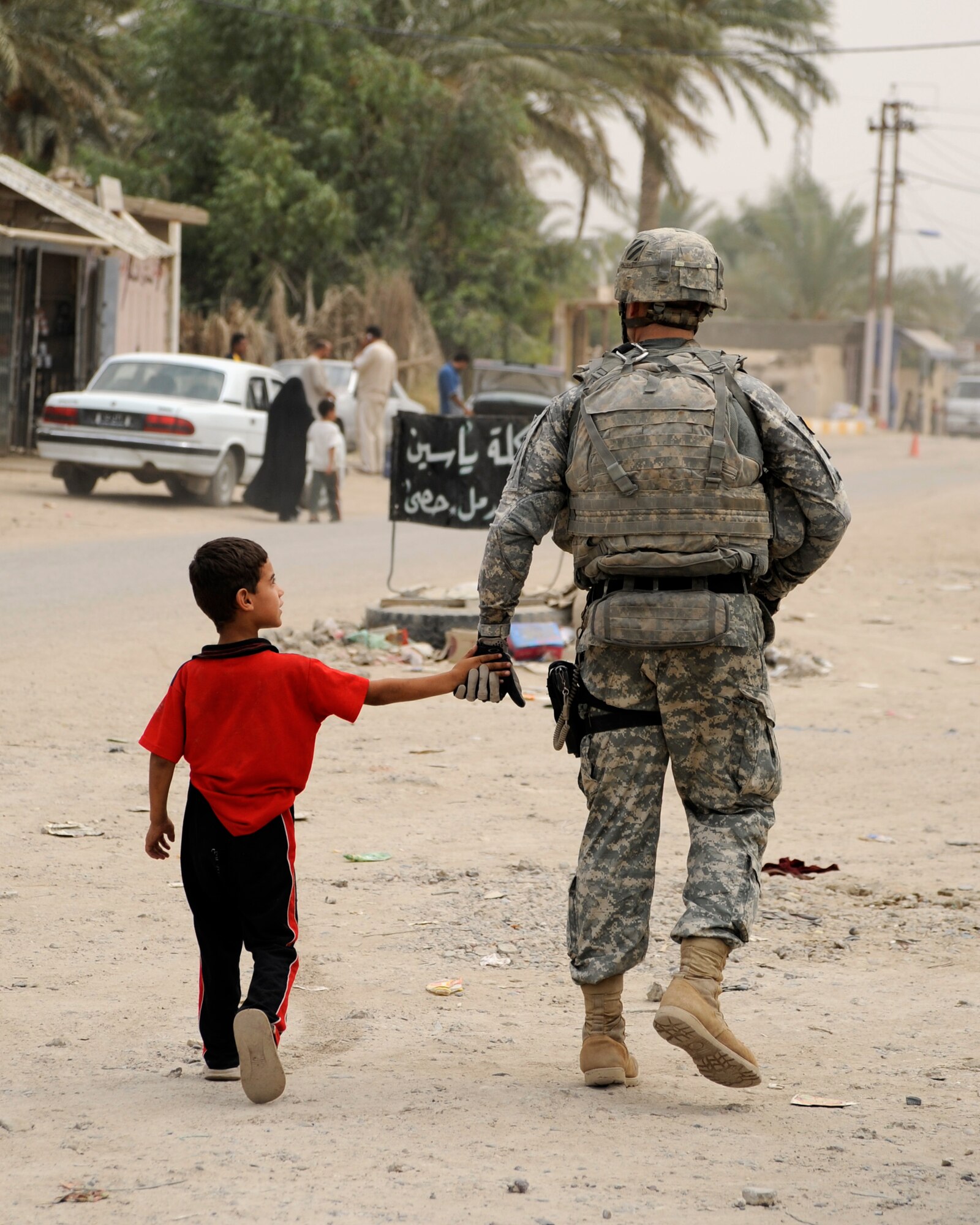 HAWR RAJAB, IRAQ -- A soldier with Alpha Troop, 6th Squadron, 8th Cavalry Regiment, walks with an Iraqi boy through the streets of Hawr Rajab, Iraq on Aug. 25. (U.S. Air Force photo/Staff Sgt. Paul Villanueva II)