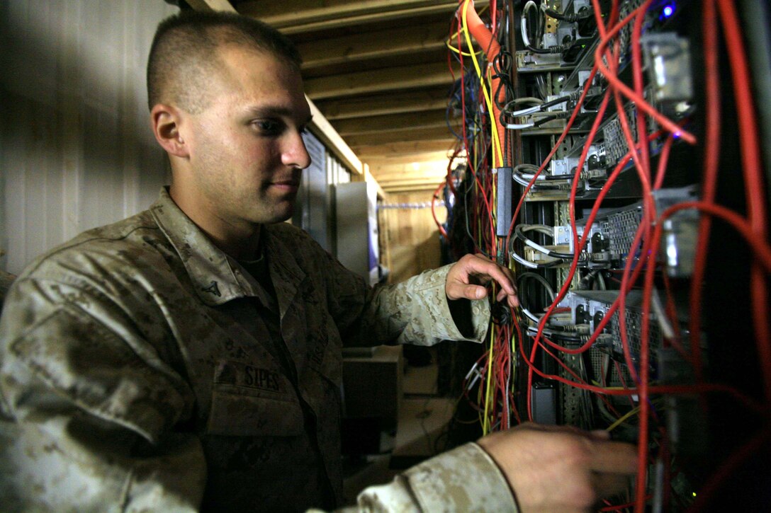 CAMP TAQADDUM, Iraq  – Lance Cpl. Jeremy J. Sipes, a Technical Control Facility administrator, from Belews Creek, N.C., performs routine maintenance on the servers at Communications Company, 1st Marine Logistics Group’s TCF here Sept. 6.  The TCF houses the servers that provide service members their internet and e-mailing capabilities.  The number of servers in the room and the Iraqi heat make it difficult to keep things cool. The building, along with others at Camp Taqaddum, has been sprayed with an insulating and fire retardant foam. This helps cool the buildings and has drastically changed the environment of the TCF. ::r::::n:: (Photo by Cpl. Tyler B. Barstow)::r::::n::