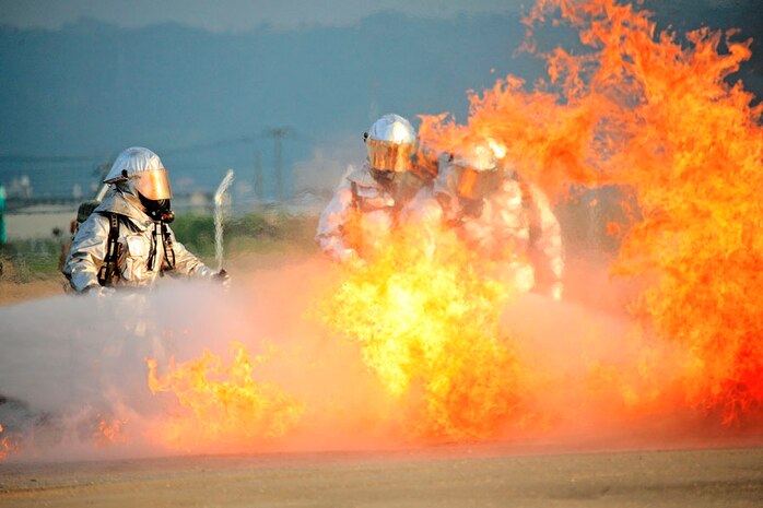 Amid 1,700-degree heat at their new training facility near the flight line here Sept. 6, teams of station aircraft rescue firefighters work to extinguish jet fuel vapors billowing as high as 200 feet in the air as part of a routine training exercise.