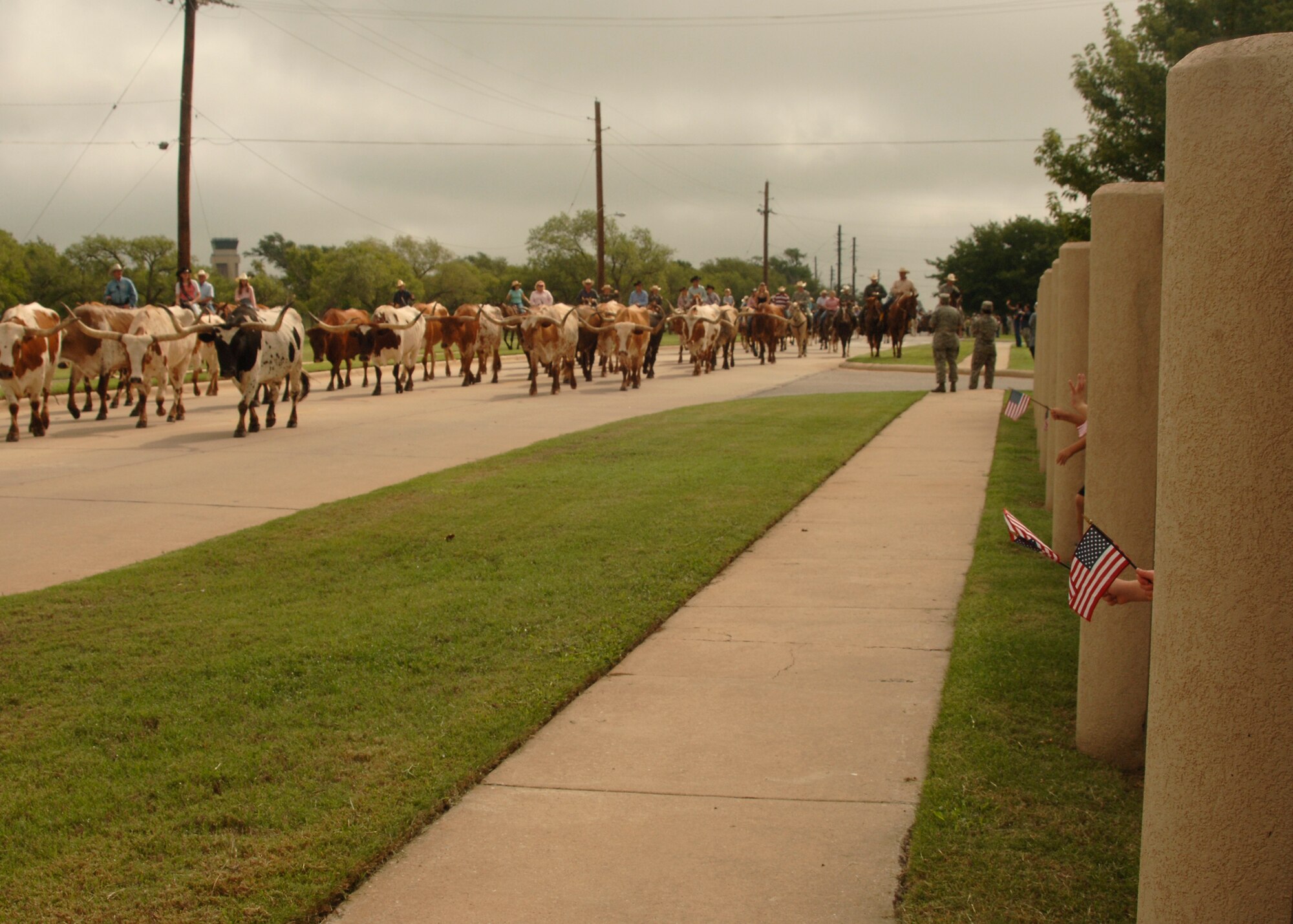 Cattle Drive going past Altus Air Force Base Child Development Center, while little hands wave American flags through the fence. (U.S. Air Force photo/Airman 1st Class Amanda Bower)