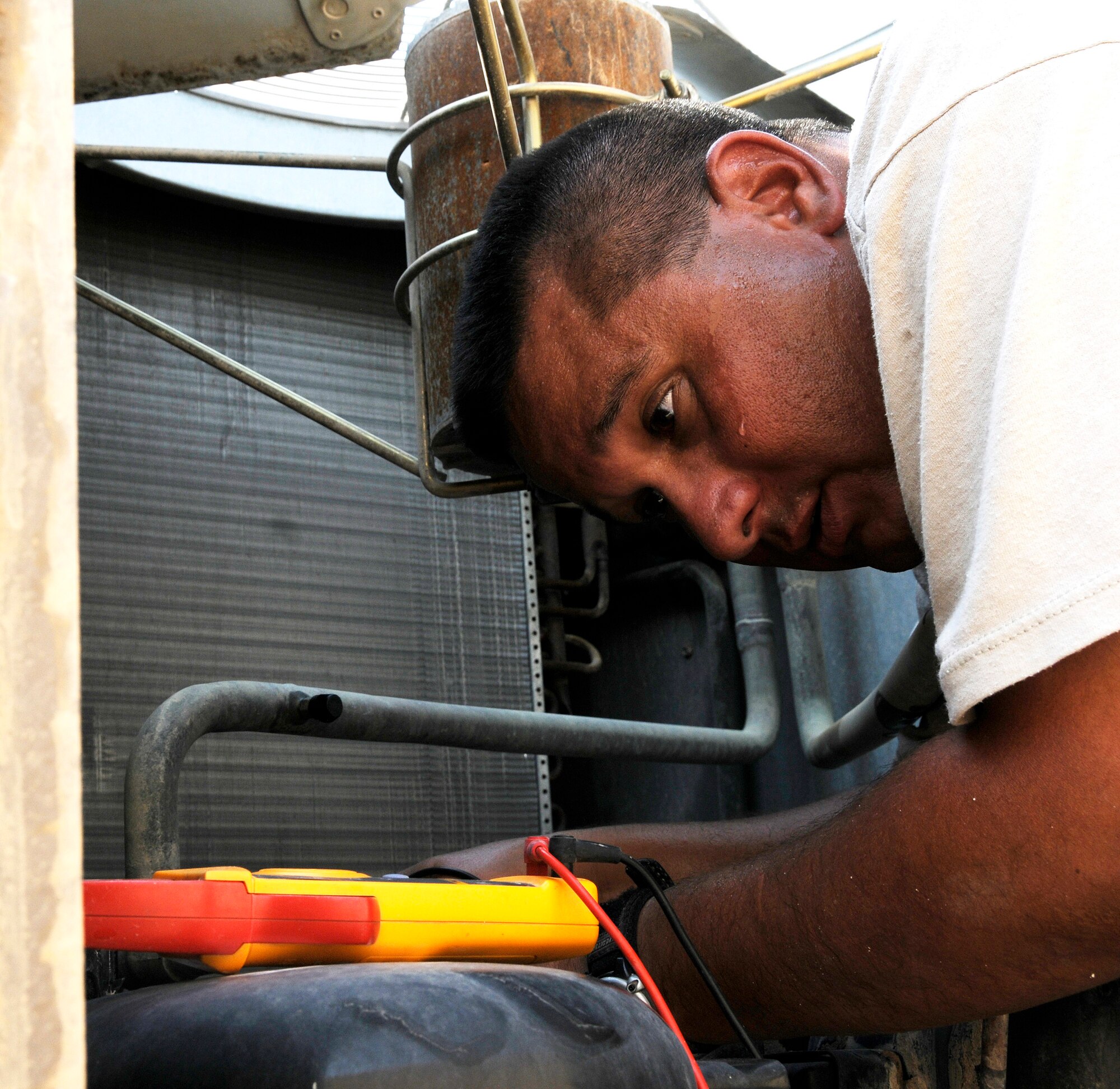 Tech. Sgt. Steven Martinez, 379th Expeditionary Civil Engineer Squadron, checks for electrical current while troubleshooting a malfunctioning air conditioning compressor Sept. 6, 2008.  The intense heat of the day is just one of the obstacles that Sergeant Martinez works through while repairing the air conditioning in the personnel quarters at this undisclosed desert location in Southwest Asia.  Sergeant Martinez is deployed from Pope Air Force Base, N.C., in support of Operations Iraqi and Enduring Freedom and Joint Task Force-Horn of Africa.  (U.S. Air Force photo by Tech. Sgt. Michael Boquette/Released)