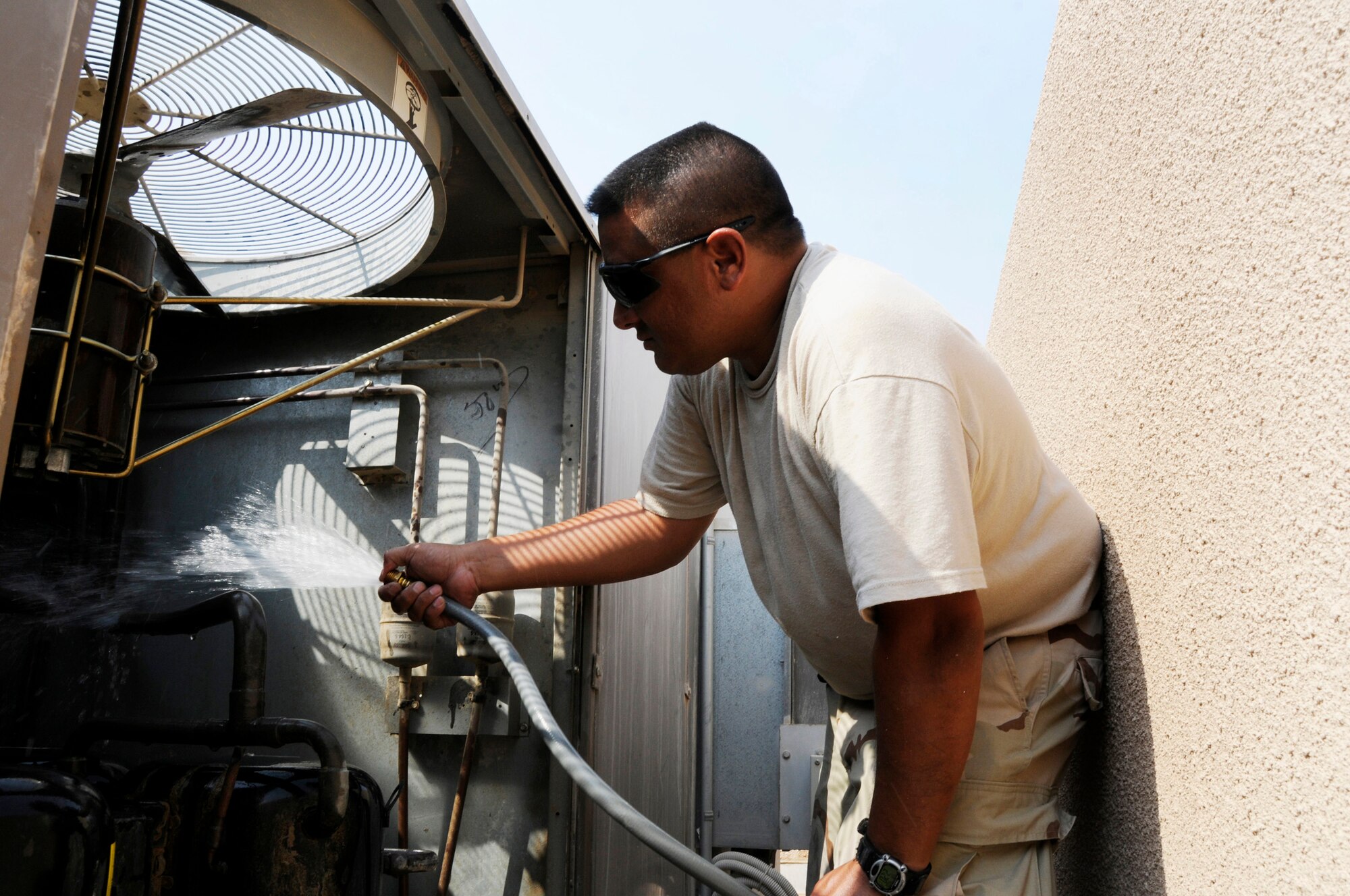 Tech. Sgt. Steven Martinez, 379th Expeditionary Civil Engineer Squadron, sprays out the condenser and compressor in a rooftop air conditioning unit Sept. 6, 2008.  The intense heat of the day is just one of the obstacles that Sergeant Martinez works through while repairing the air conditioning unit in the personnel quarters at this undisclosed desert location in Southwest Asia.  Sergeant Martinez is deployed from Pope Air Force Base, N.C., in support of Operations Iraqi and Enduring Freedom and Joint Task Force-Horn of Africa.  (U.S. Air Force photo by Tech. Sgt. Michael Boquette/Released)