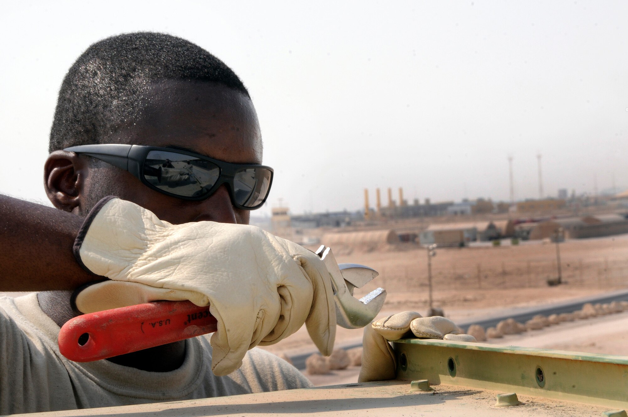 Senior Airman Stephen James, 379th Expeditionary Civil Engineer Squadron, prepares to loosen a screw on the fresh air intake cover Sept. 6, 2008.  Removing the cover is the first step in a routine cleaning of the air handler intake system.  Work on the roof of personnel quarters here at this undisclosed desert location in Southwest Asia is incredibly hot.  Airman James, a native of Miami, Fla., is deployed from Andrews Air Force Base, Md., supporting Operations Iraqi and Enduring Freedom and Joint Task Force-Horn of Africa.  (U.S. Air Force photo by Tech. Sgt. Michael Boquette/Released)