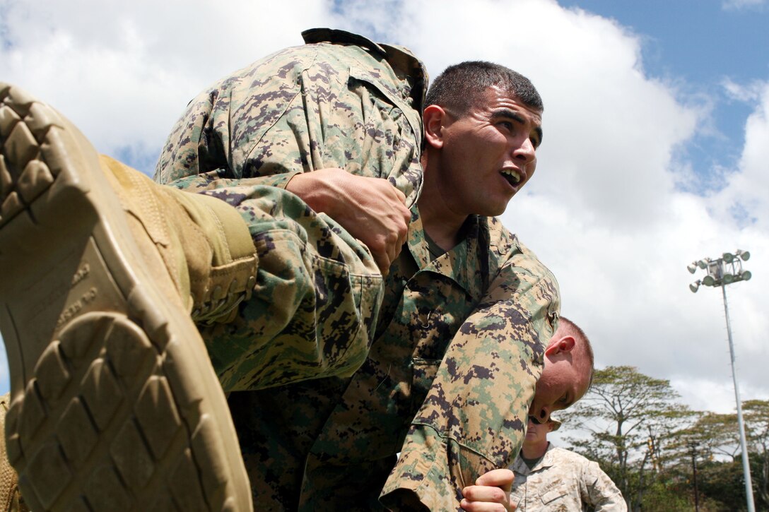 Staff Sgt. David Rubio, Ordnance Manager for Headquarters and Service Battalion, U.S. Marine Corps Forces, Pacific, fireman carries Cpl. John Beckley, bachelor enlisted quarters assistant manager for Headquarters and Service Battalion, MarForPac, during the Training and Education Command combat fitness test road show demonstration held at Bordelon Field Sept. 8.