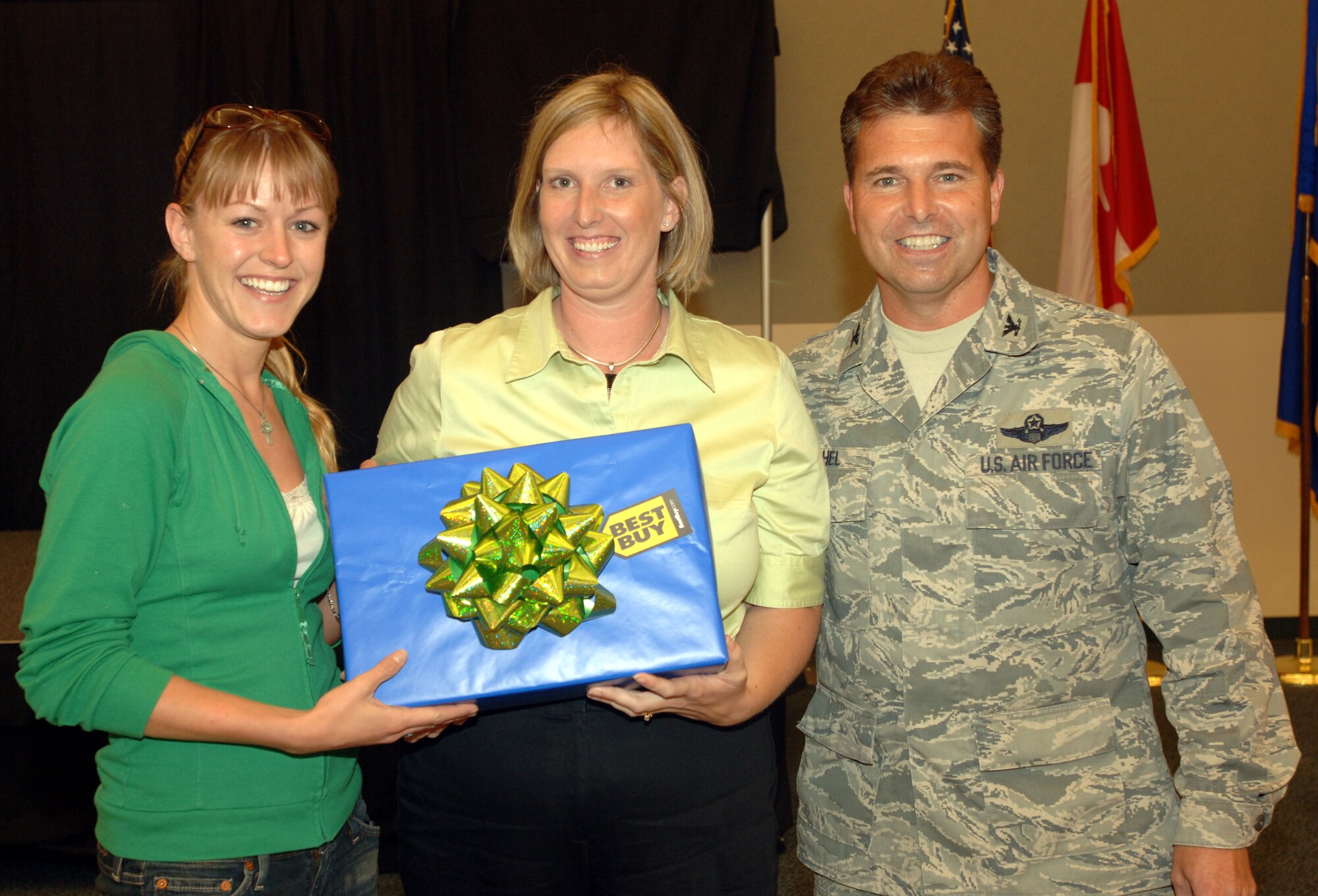 2nd Lt. Elizabeth Brende (L), 319th Communications Squadron accepts her Nintendo Wii system from Mrs. Heather Goodwin (C), spouse of Maj. Michael Goodwin, 319th Air Refueling Wing; and Col. John Michel, 319 ARW commander at Military Appreciation Day Aug. 28.  Lt. Brende was awarded the game system for her winning the best energy savings idea contest sponsored by the wing.  Her idea was to install motion detector switches in place of all light switches on base. No federal endorsement of Nintendo or Best Buy is given or implied. (U.S. Air Force photo/Tech. Sgt. Joseph Kapinos)