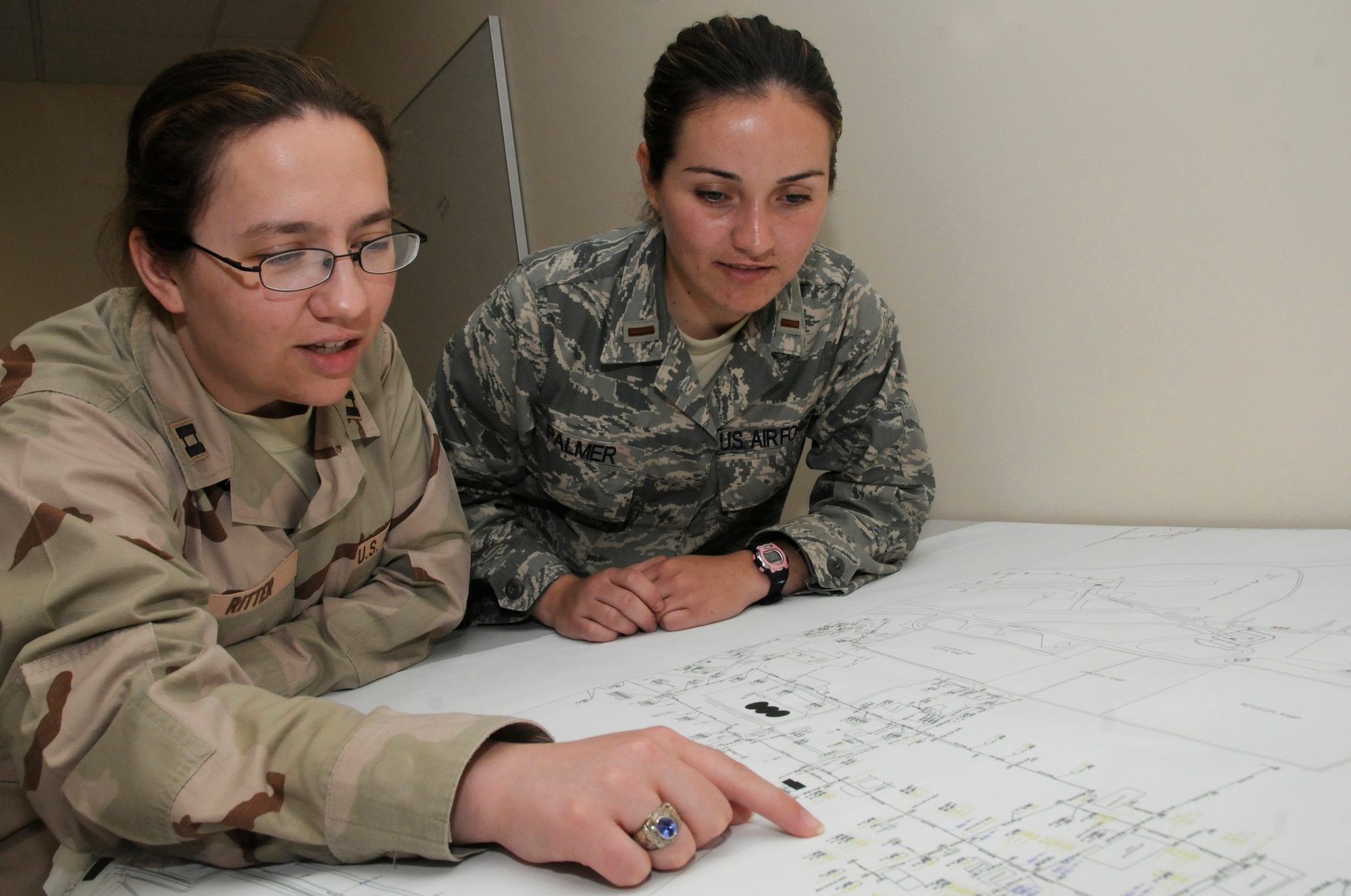Capt. Kalli Ritter shows her replacement, 2nd Lt. Alyssa Palmer, future expansion plans at an undisclosed air base in Southwest Asia Sept. 7, 2008. Both officers are project managers for the 379th Expeditionary Communications Squadron. Project managers here are directly involved in turning the base from expeditionary to an enduring base in support of Operations Iraqi and Enduring Freedom and Joint Task Force-Horn of Africa. Captain Ritter, a native of Howell, Mich., is deployed from Lajes Field, Portugal, and Lieutenant Palmer, a native of Corvallis, Ore., is deployed from Tinker Air Force Base, Okla.  (U.S. Air Force photo by Staff Sgt. Darnell T. Cannady/Released)